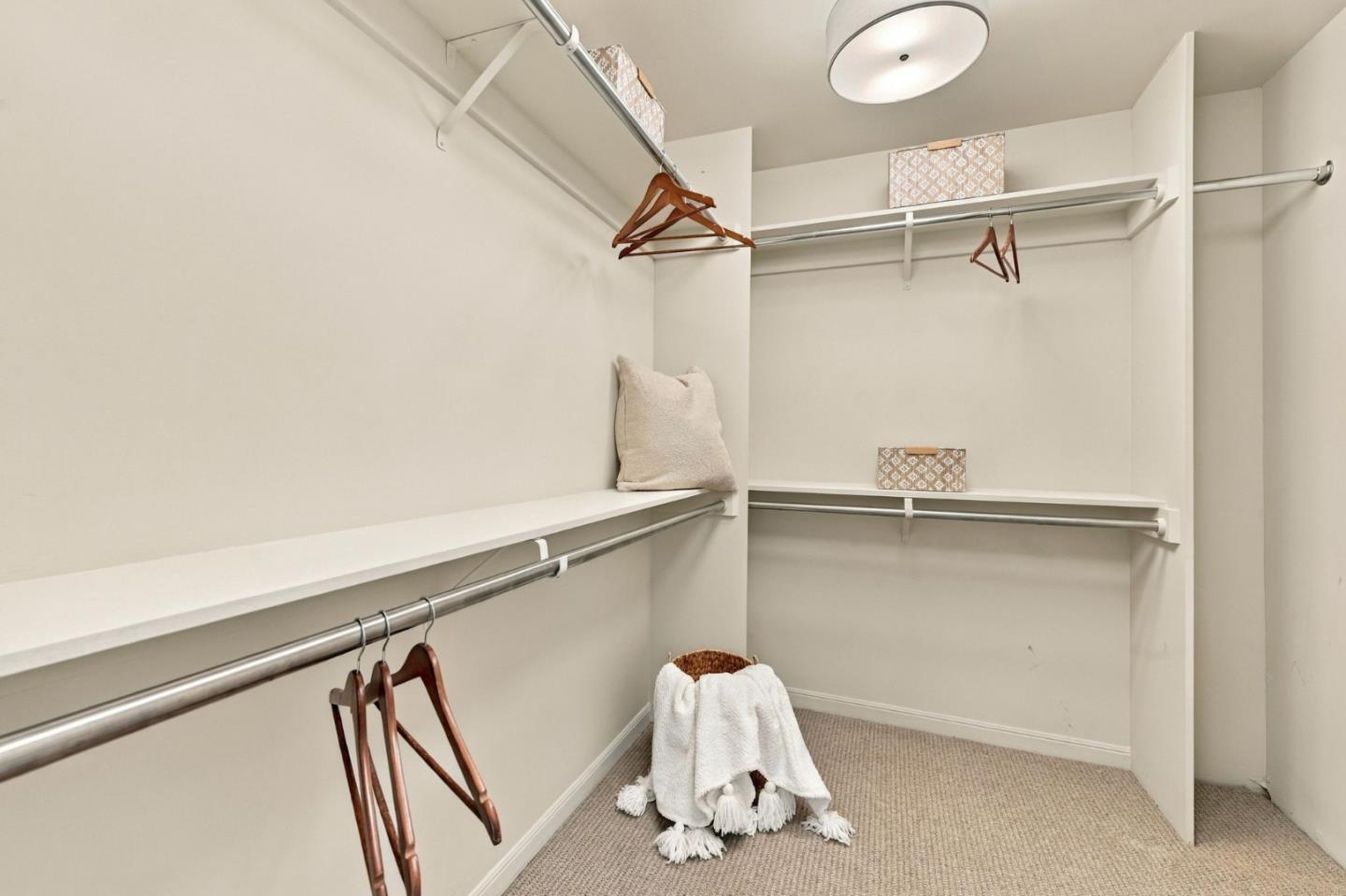 Walk-in closet with built-in shelves, hanging rods, and towels arranged on the floor.
