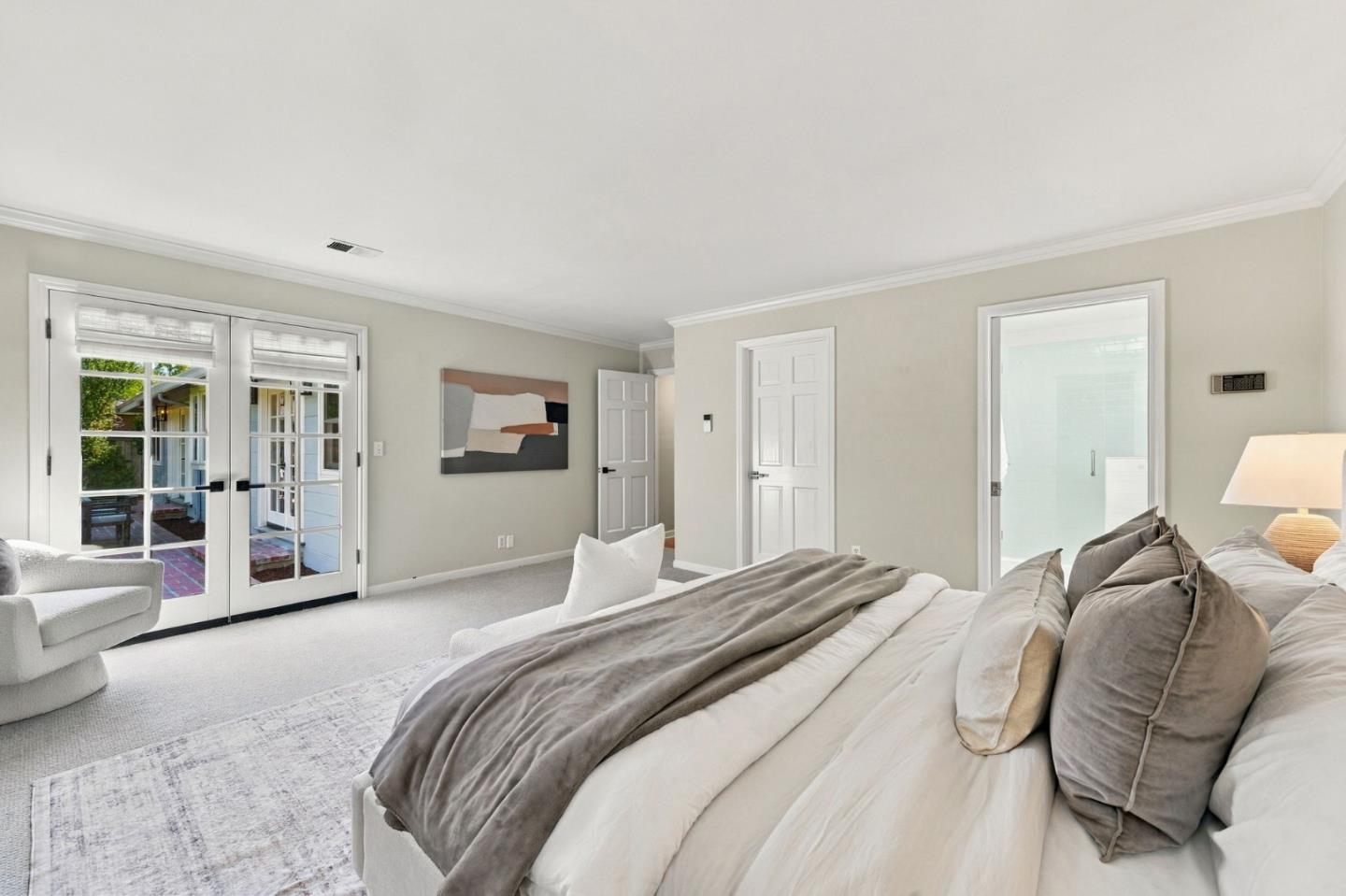 Furnished bedroom with a large bed and white French doors opening to a patio.