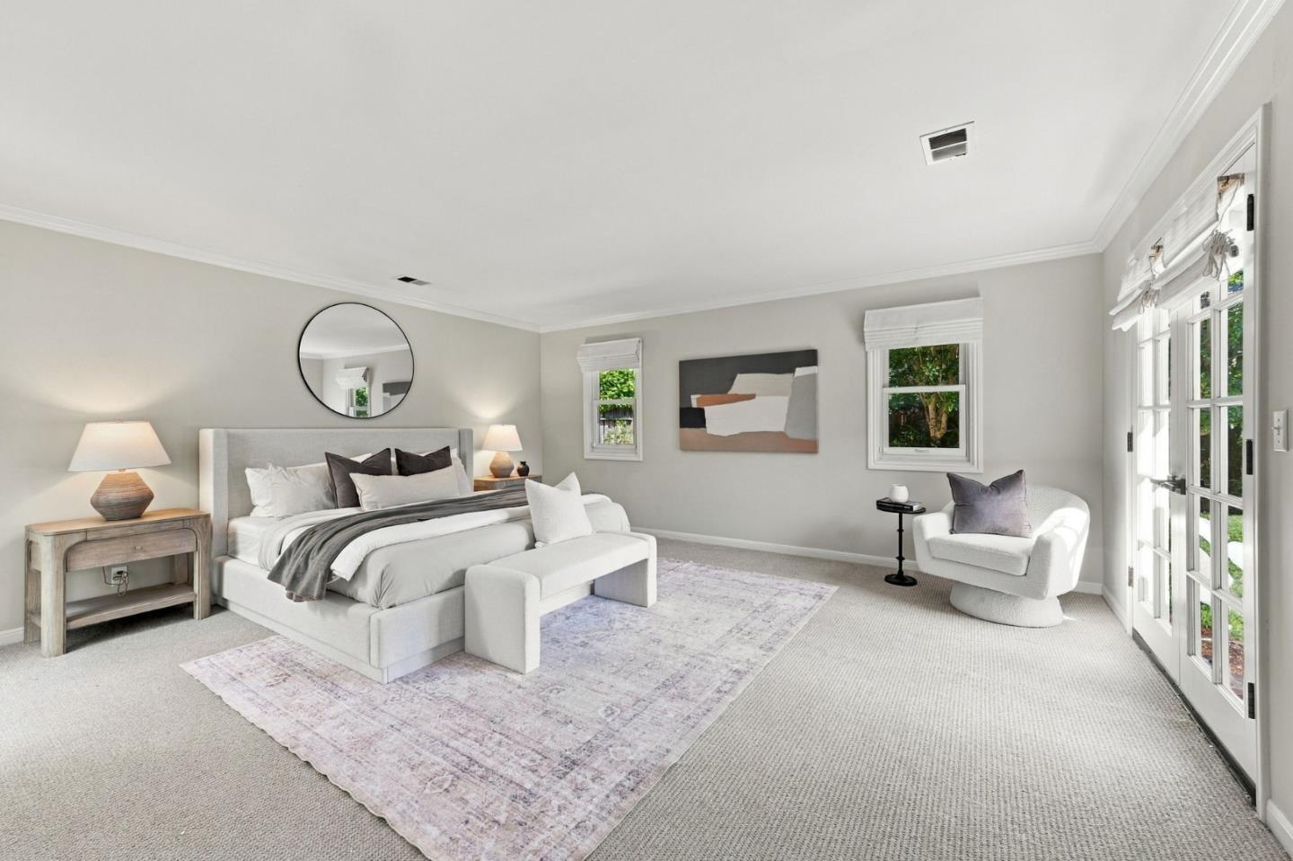 Staged bedroom with an upholstered bed and bright French doors opening to the garden.