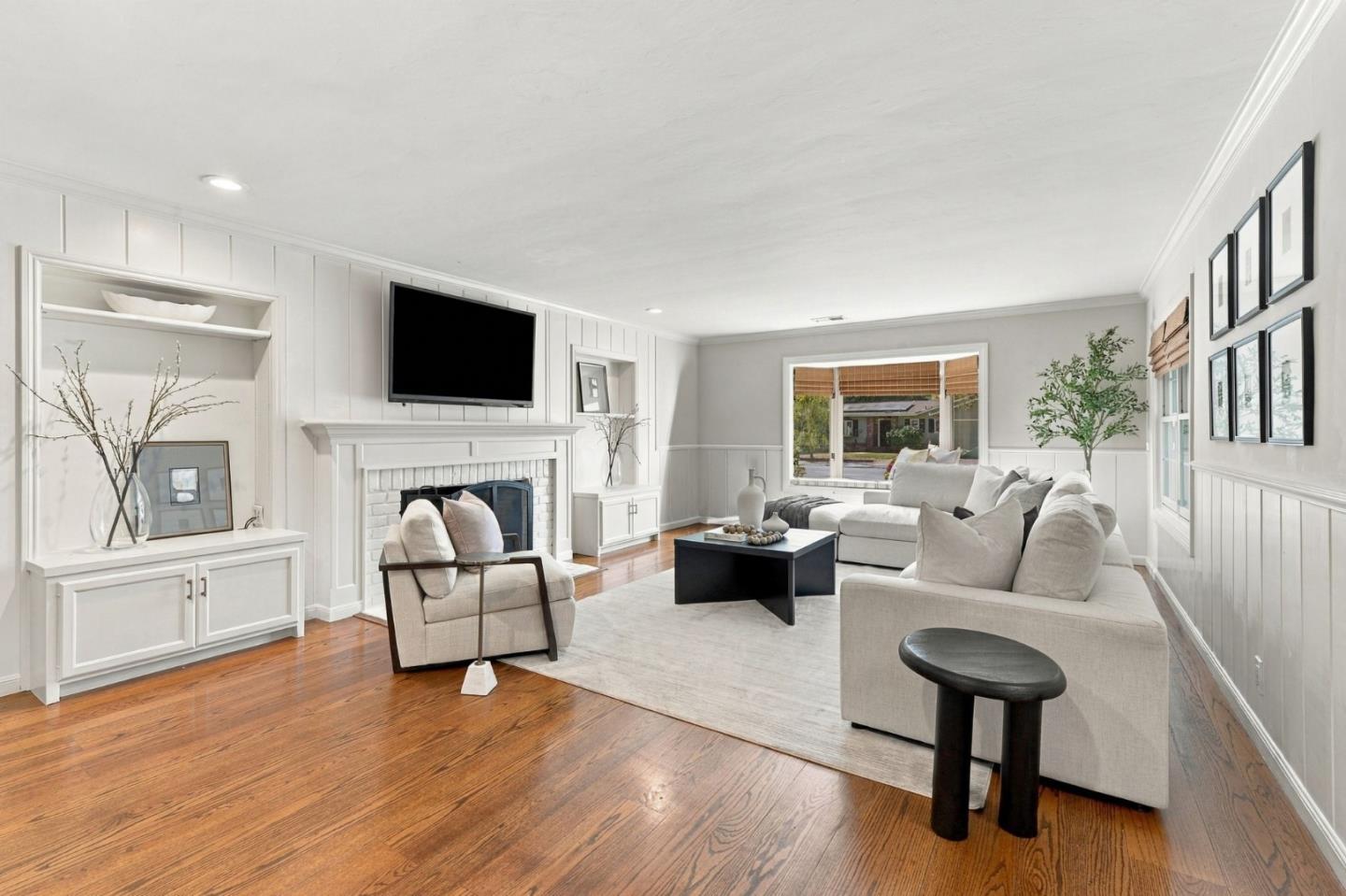 Staged living room with a white brick fireplace, built-in cabinets, and warm wood floors.