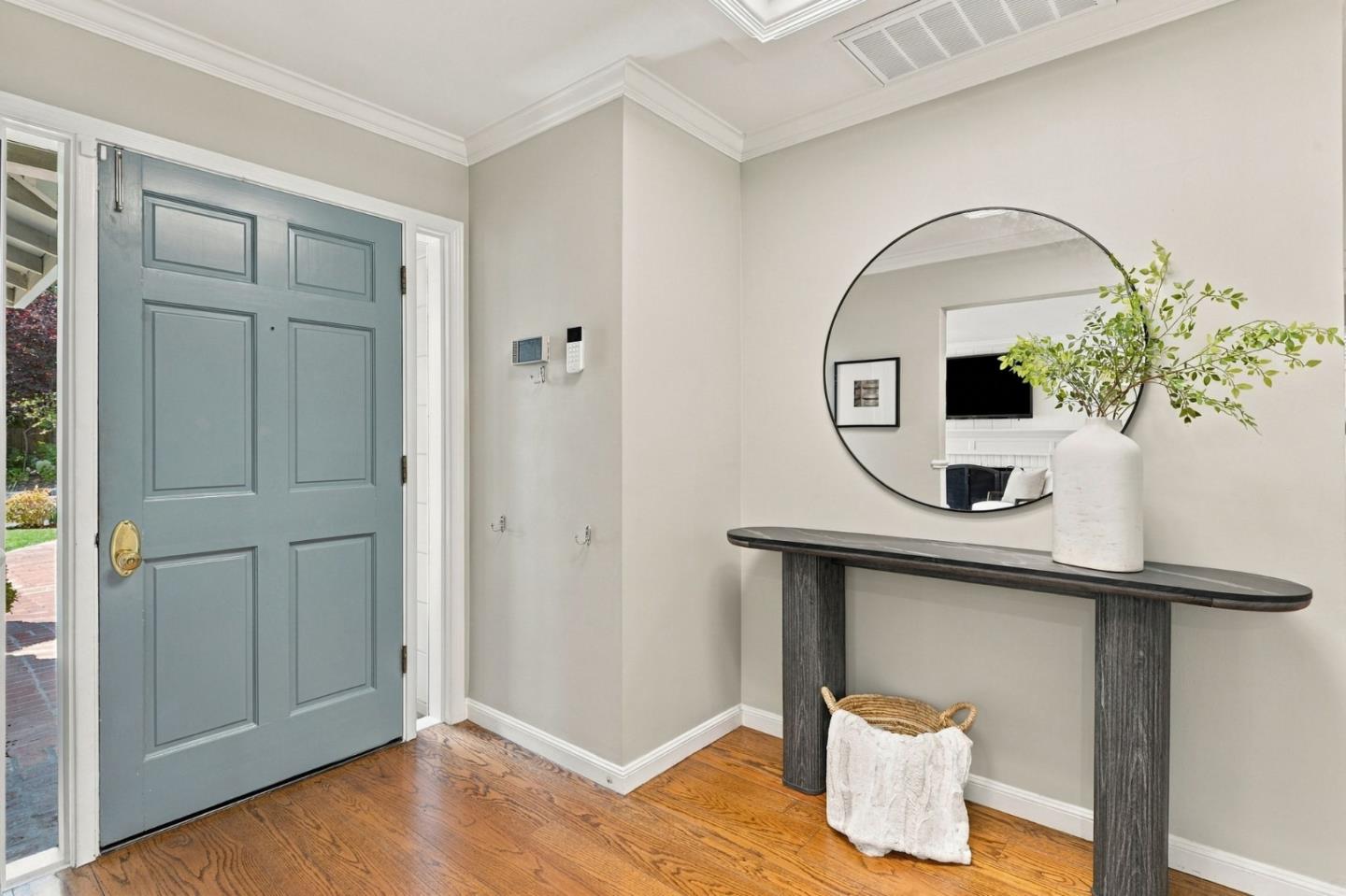 Entryway with a blue paneled front door, hardwood floors, and a console table beneath a round mirror.