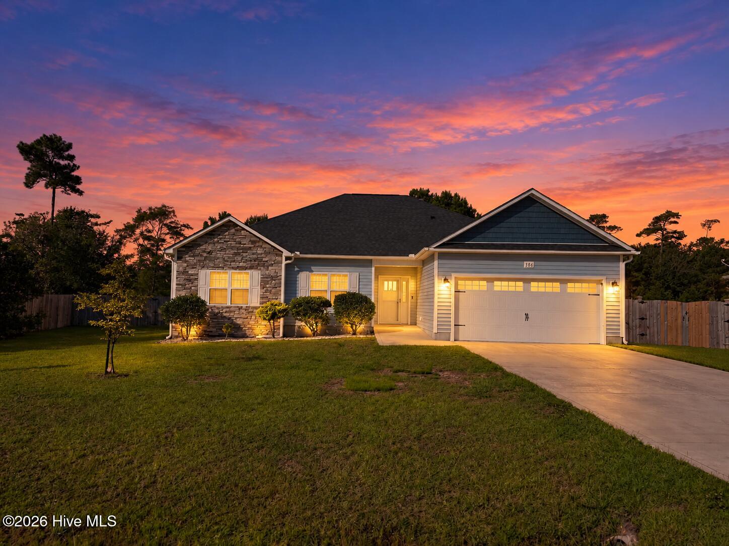 Single-story home with a stone facade and warmly lit entry at sunset.