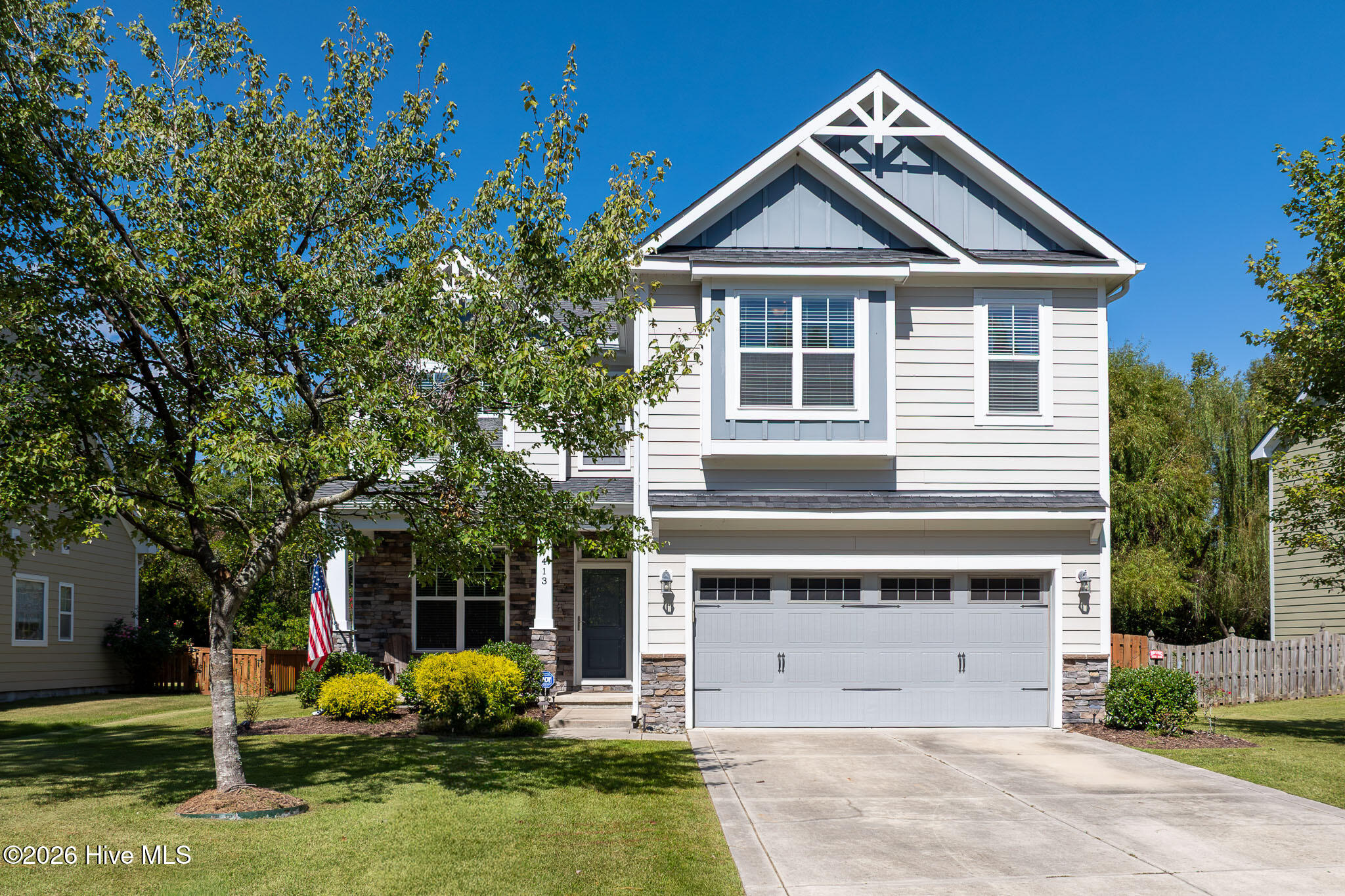 Two-story white home with a prominent gabled roof, stone accents, and an attached garage.