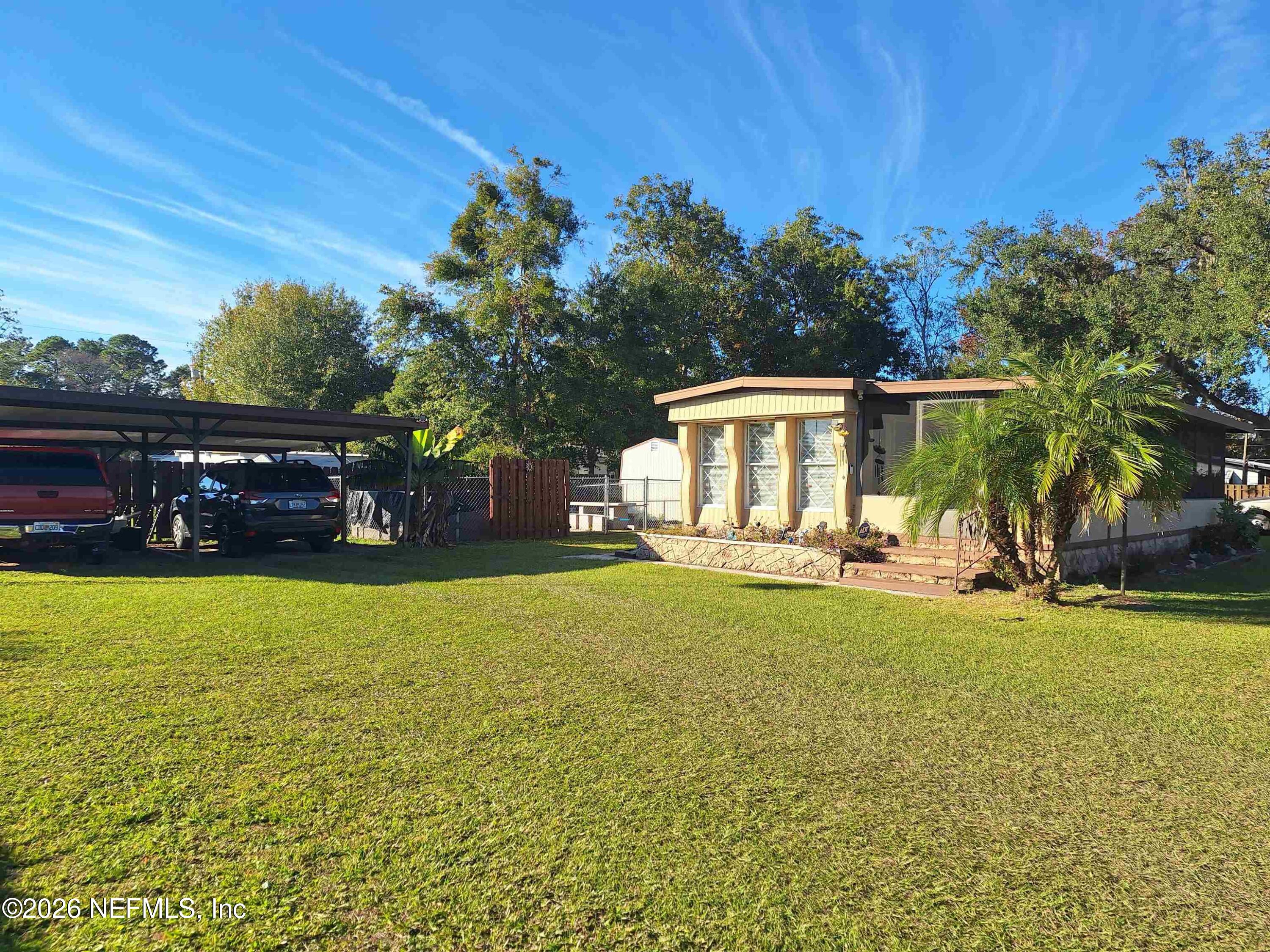 Single-story home with a covered carport, palm tree, and broad front lawn.