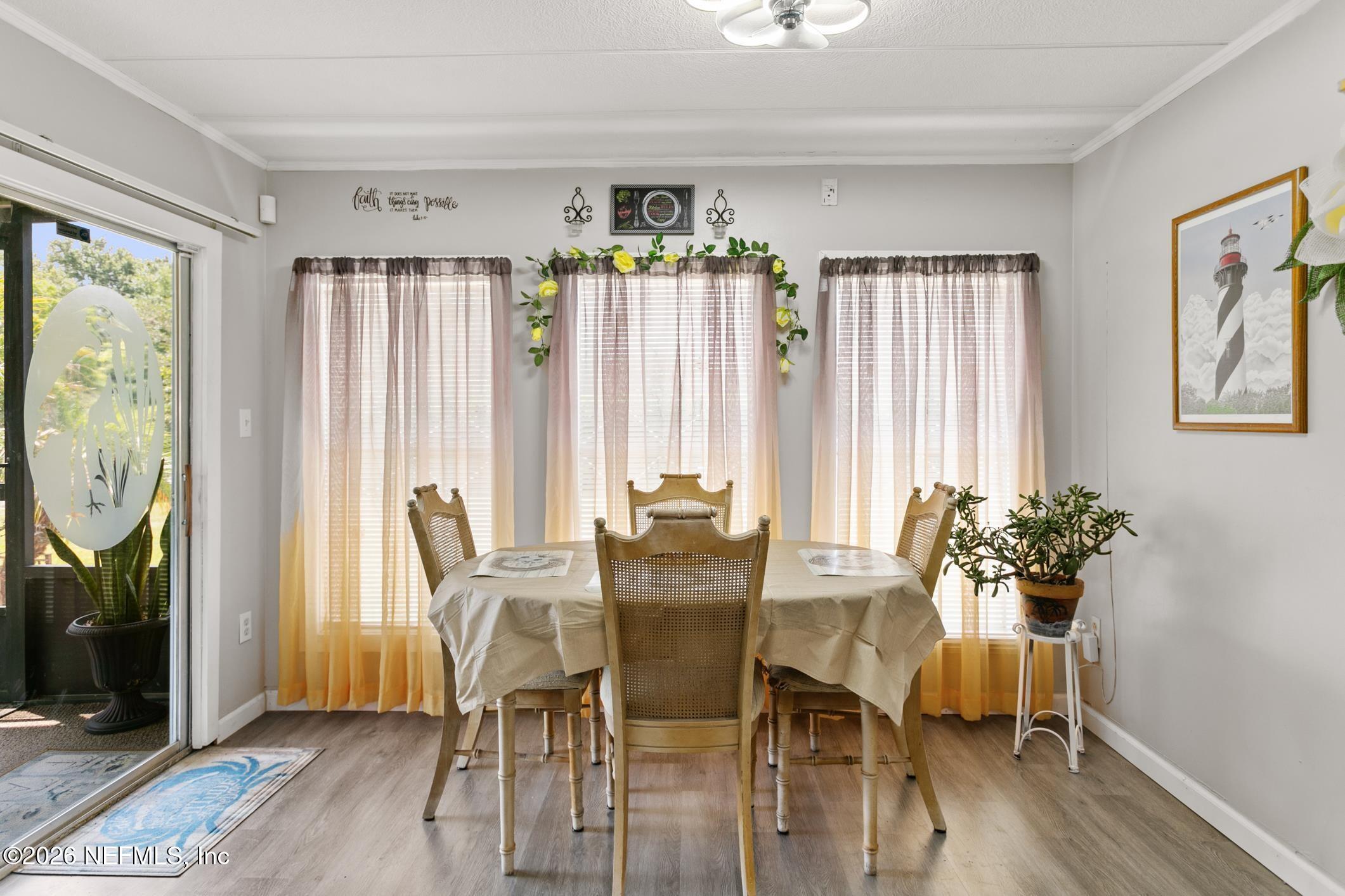 Dining room with a cane-back dining set, three curtained windows, and a sliding glass door.