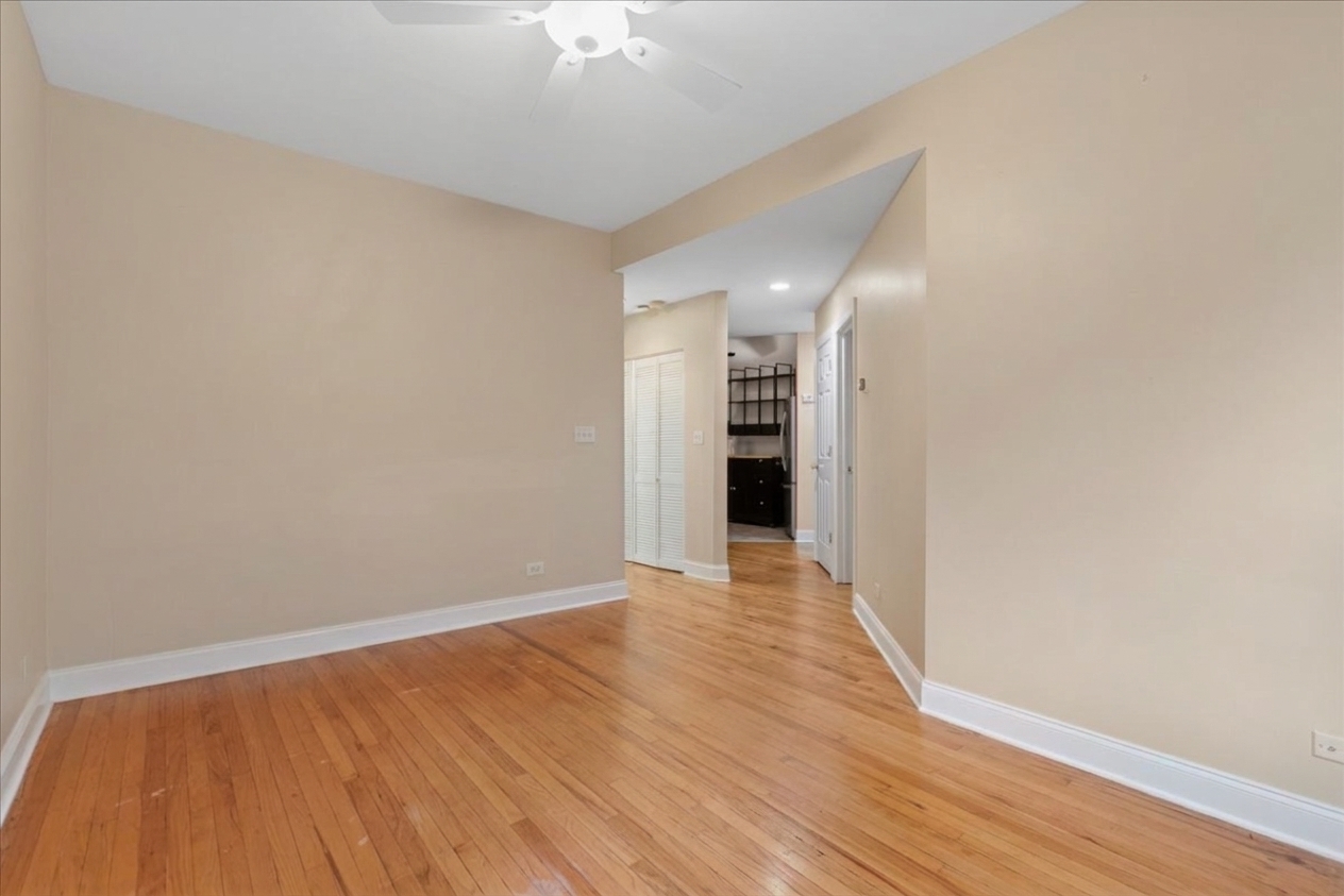 Empty living room with hardwood floors and an open passage to the hallway.