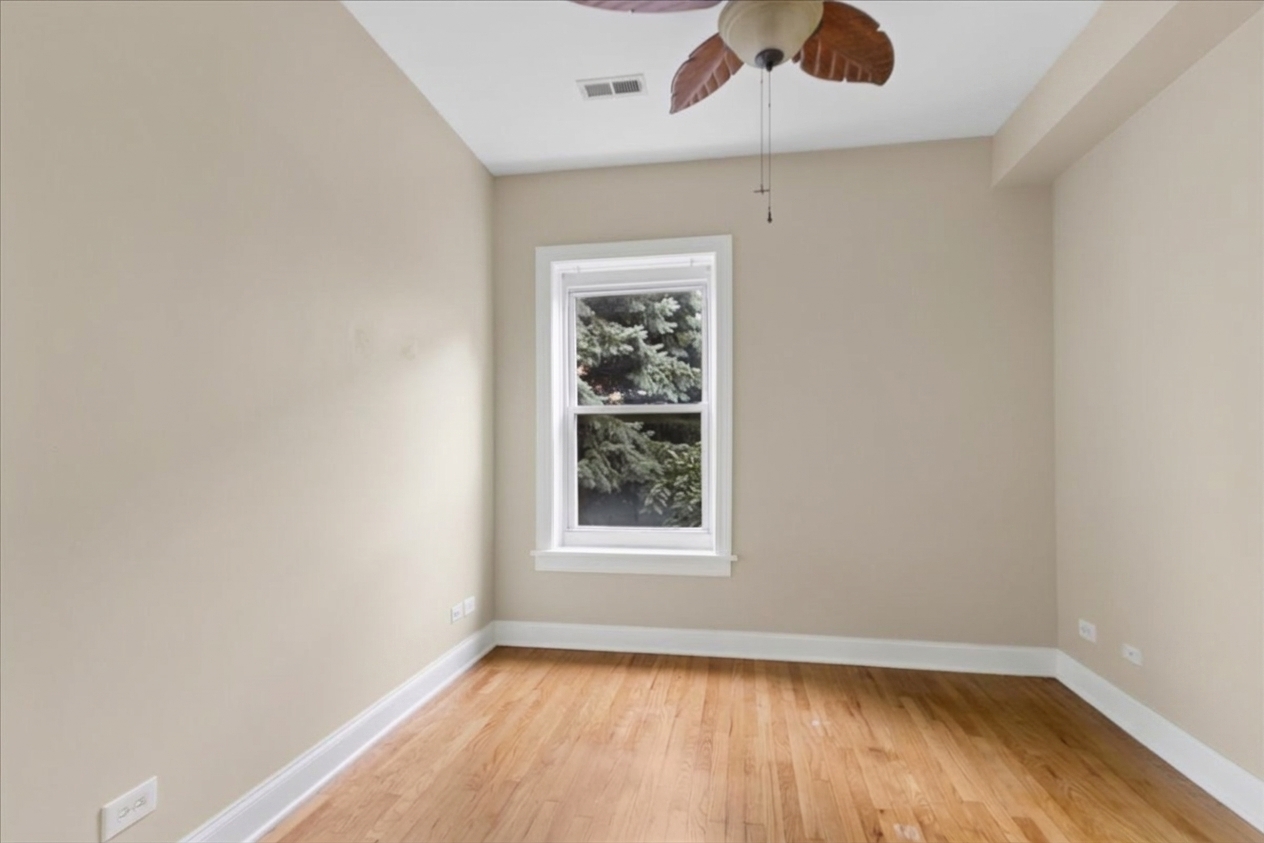 Empty bedroom with hardwood floors, a single window, and a ceiling fan.