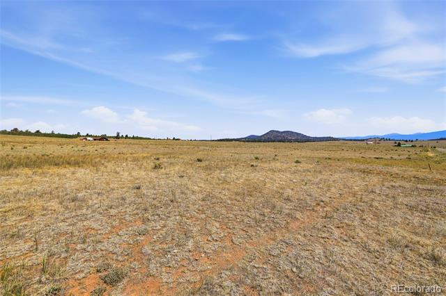 Open, dry grassy parcel with sparse vegetation and distant low mountains beneath a partly cloudy sky.
