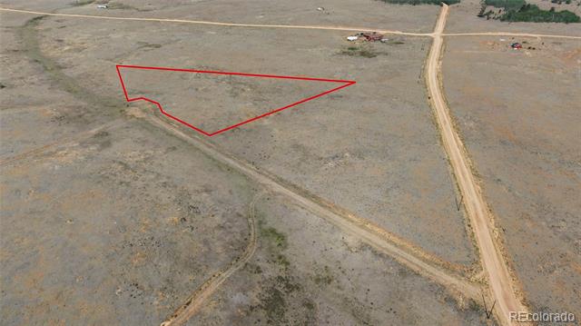 Aerial view of a dry vacant parcel outlined in red beside intersecting dirt roads.