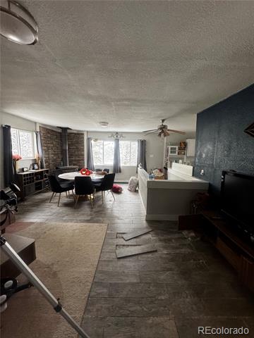Open living and dining area with gray tile floors, a round table, and dark teal accent wall.
