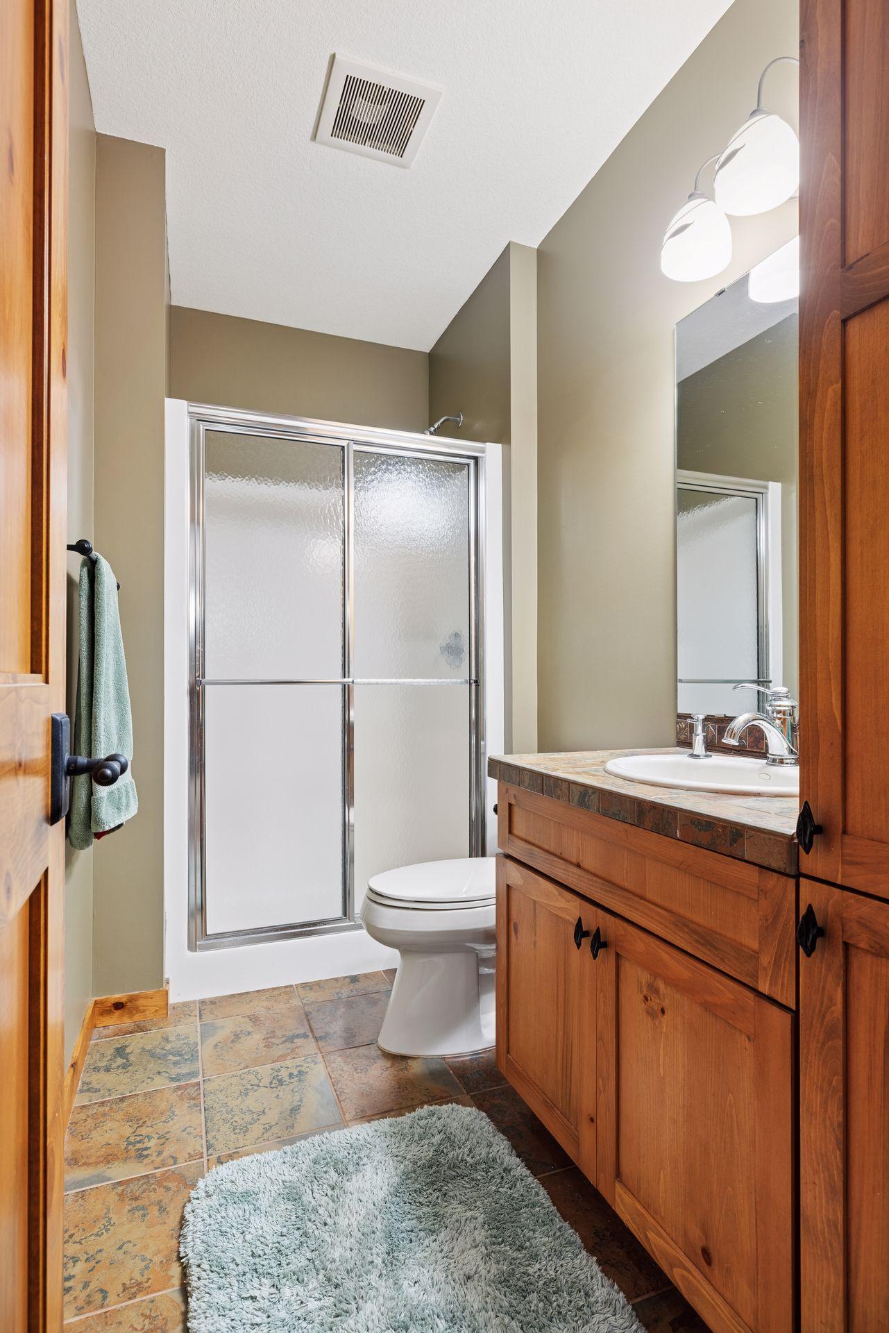 Bathroom with a frosted-glass shower and warm wood vanity.