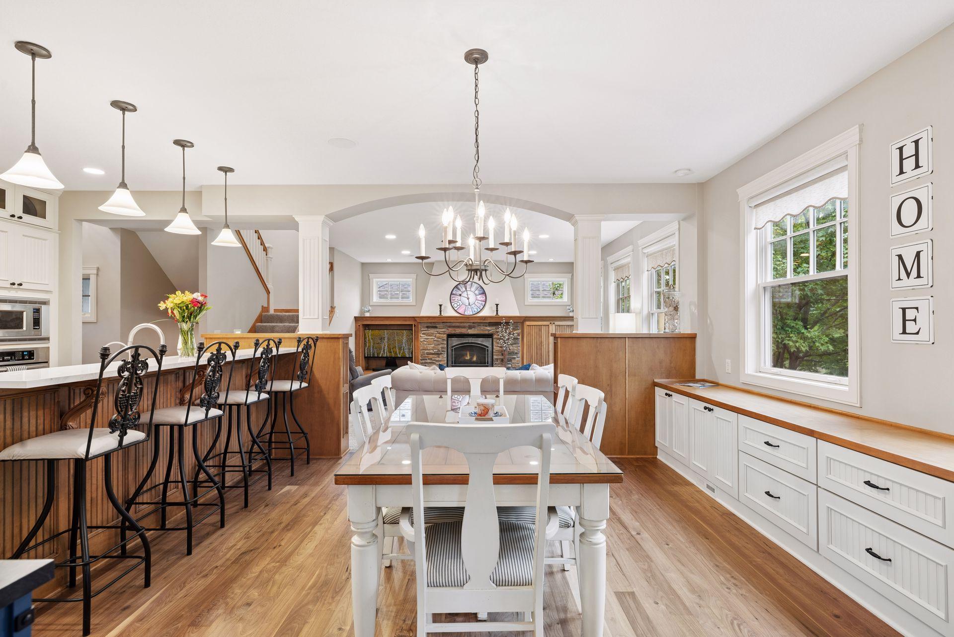 Open-plan kitchen and dining area with a wood island, white table, and stone fireplace.