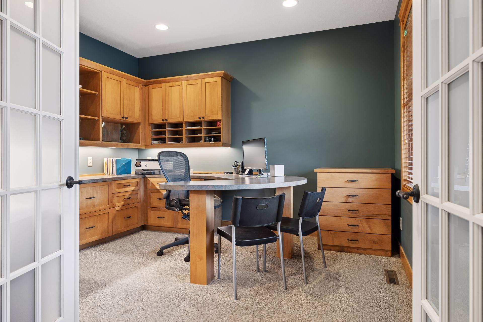 Home office with built-in wood cabinetry, a round desk, and glass-paneled French doors.