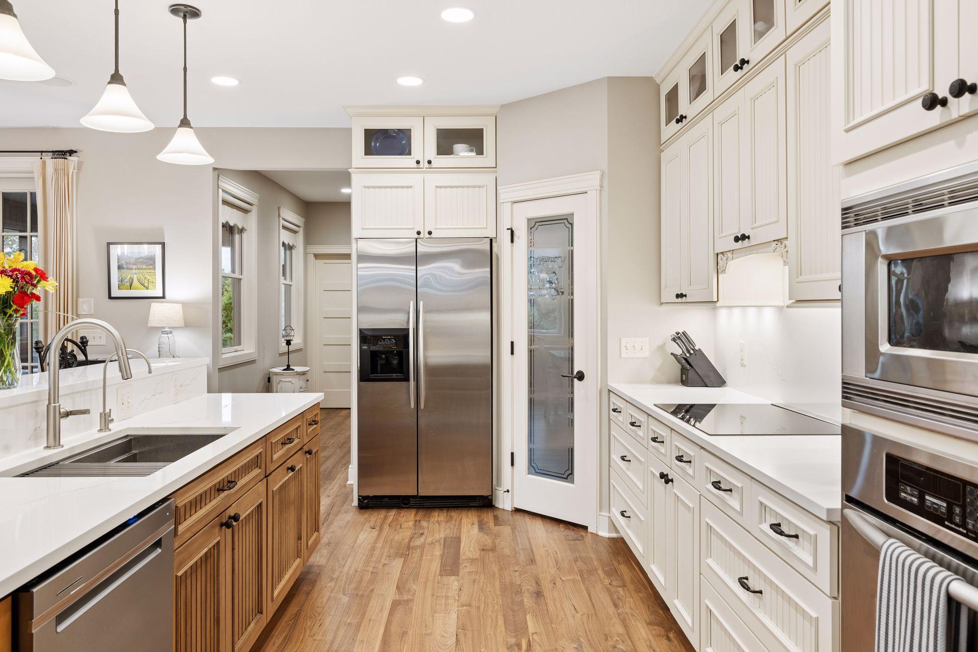 Kitchen with white cabinetry, stainless steel appliances, and a wood-front island with farmhouse sink.