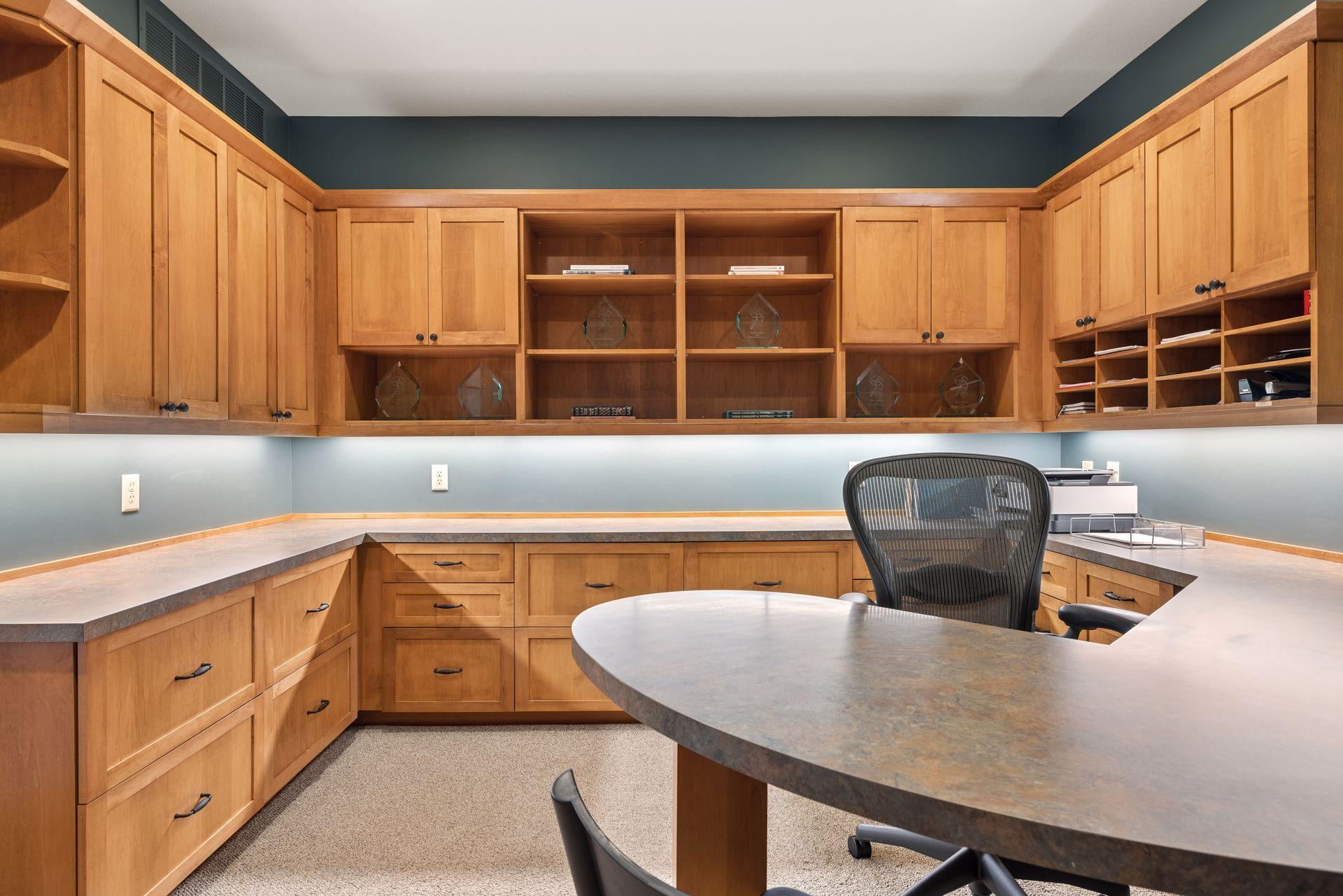 Home office with extensive wood cabinetry, open shelves, and wraparound counters.