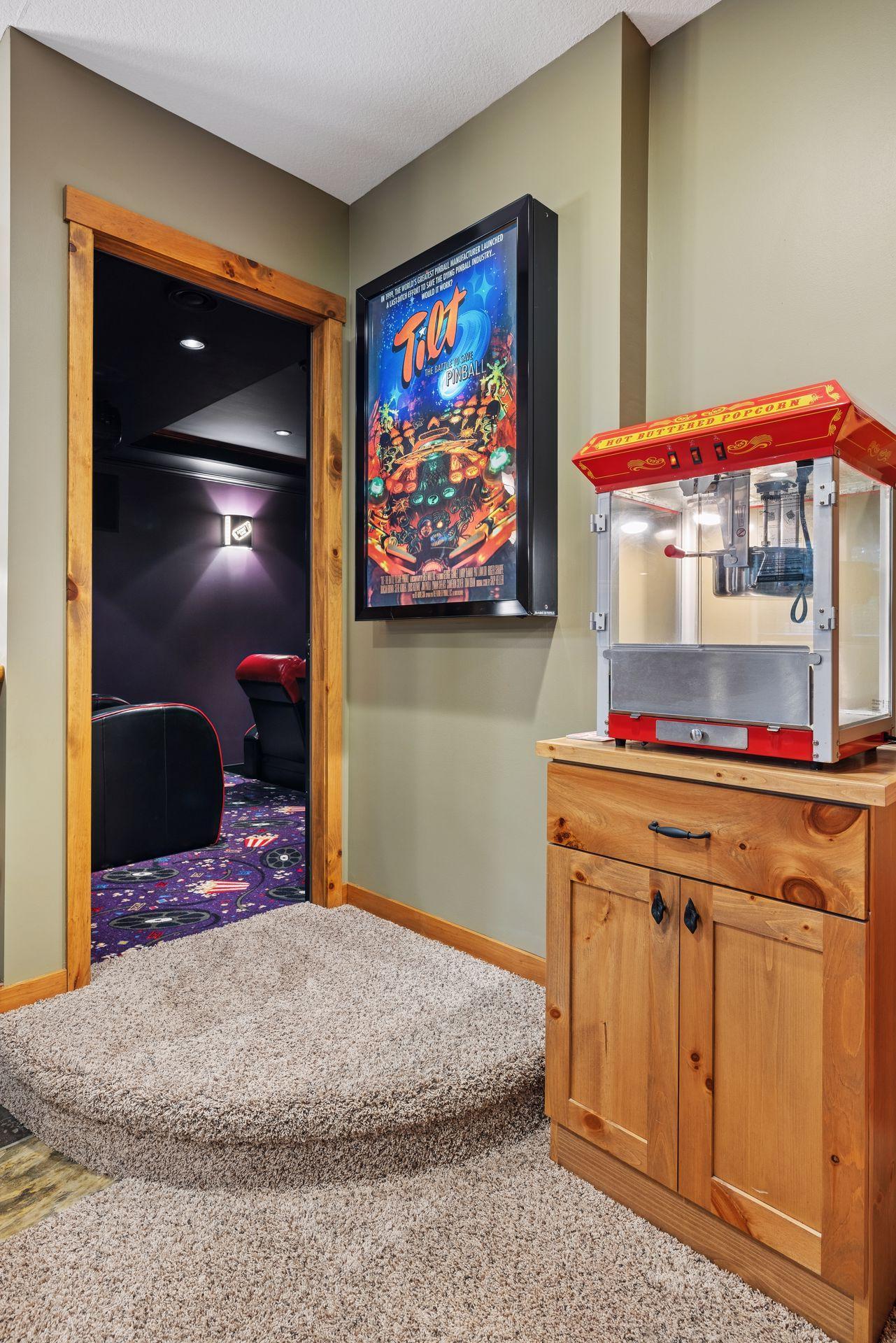 Basement entertainment area with a popcorn machine beside a doorway to a dark home theater.