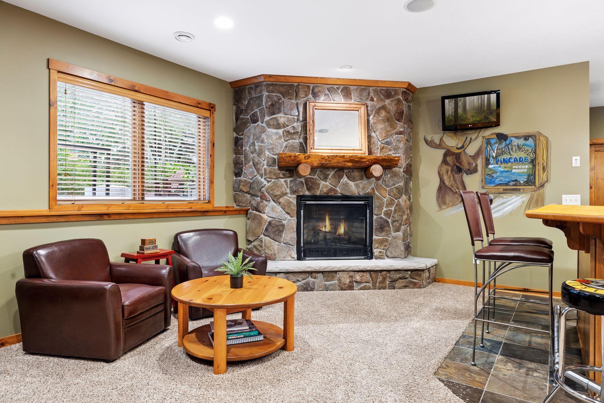 Lounge with a stone fireplace, leather armchairs, and a moose mural beside a bar counter.
