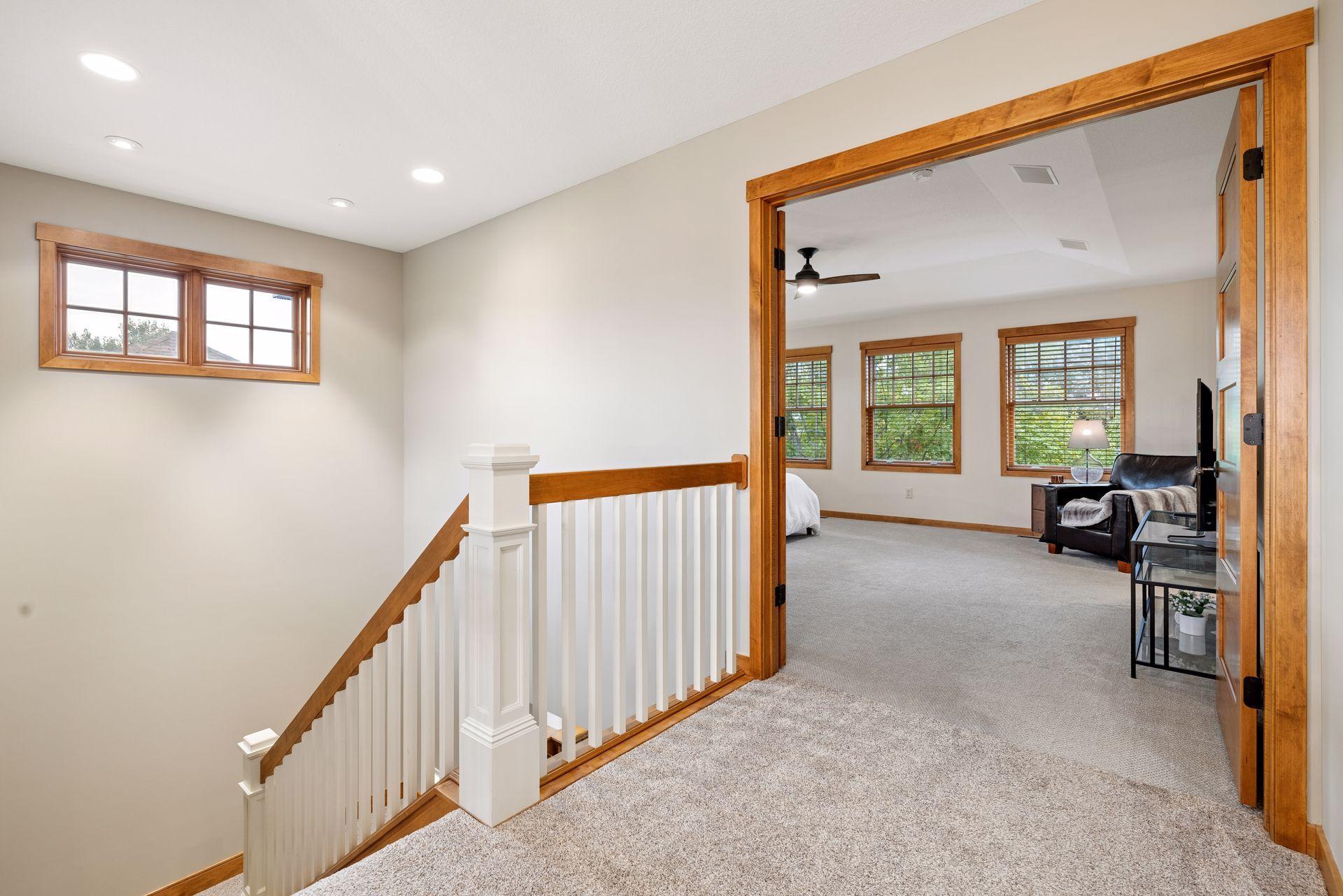 Upstairs landing with white stair railing and a wood-trimmed doorway to a furnished room.