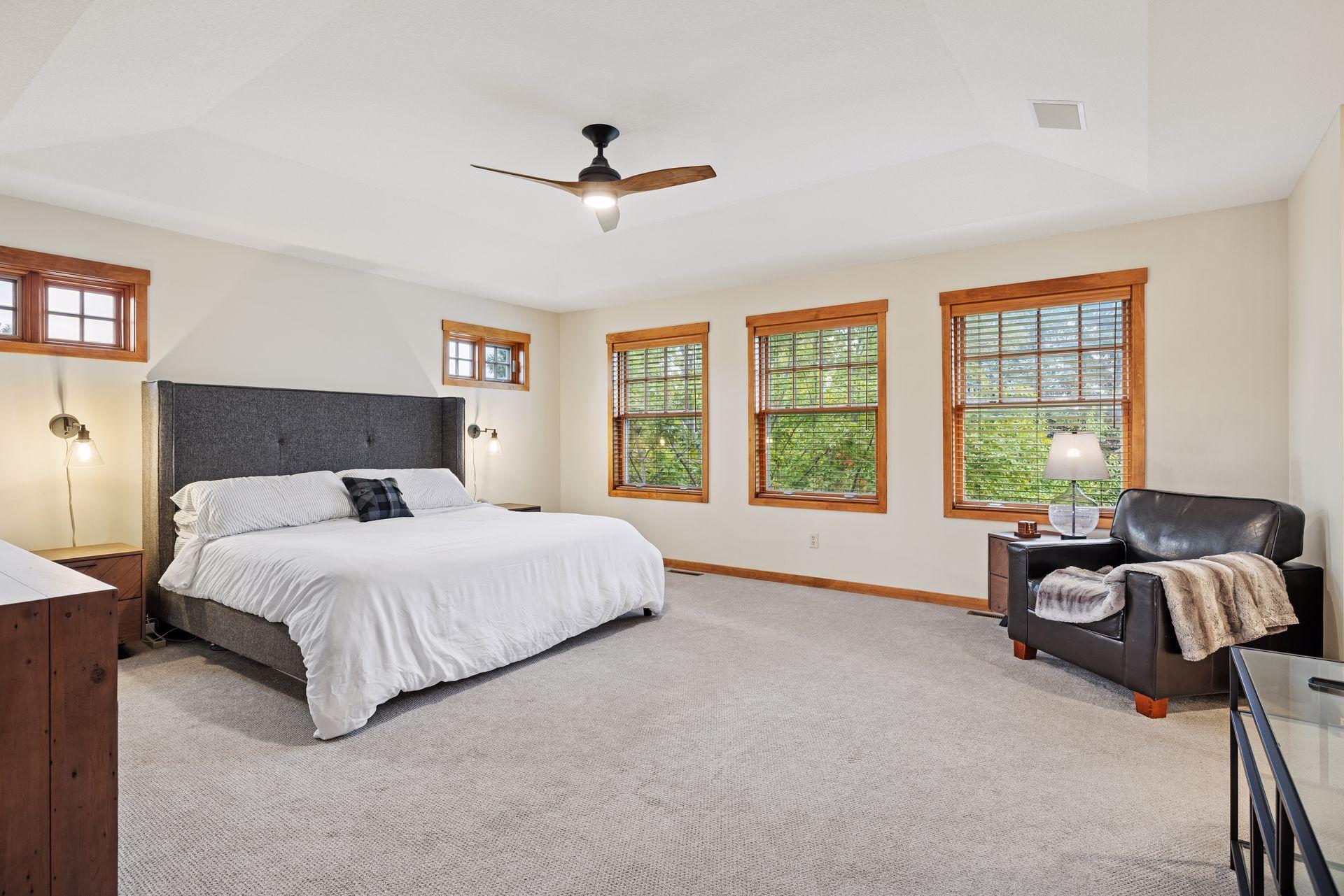 Spacious bedroom with a king-size bed, wood-trimmed windows, and a leather armchair.