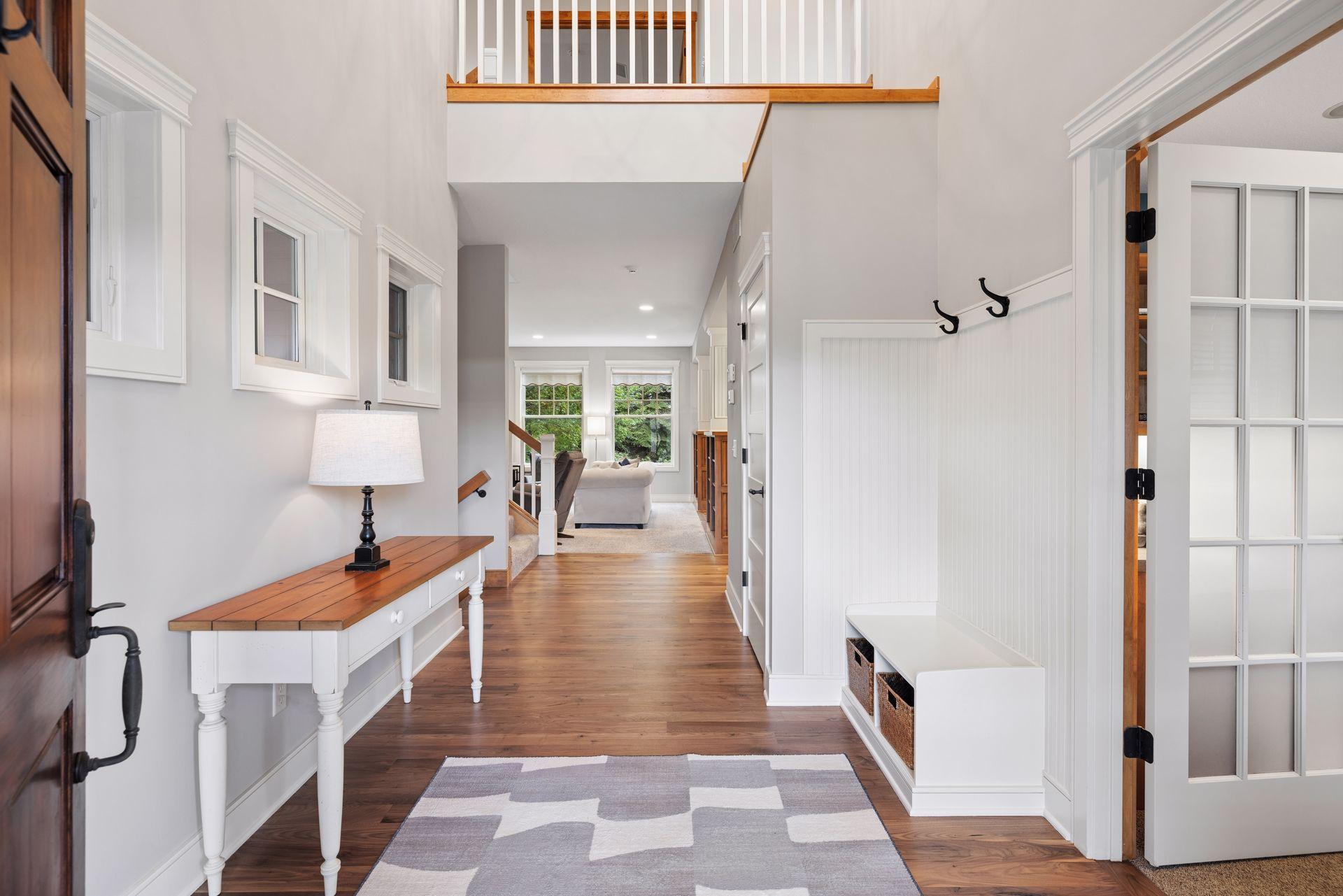 Entry hall with hardwood floors, built-in bench and coat hooks, opening toward a living room.
