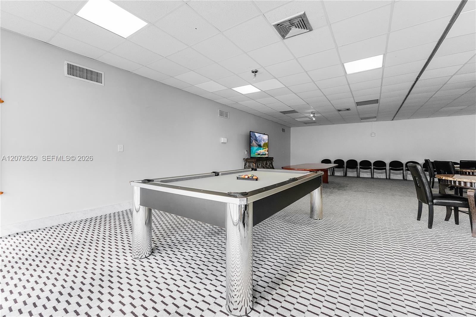Community recreation room with a pool table and rows of chairs.
