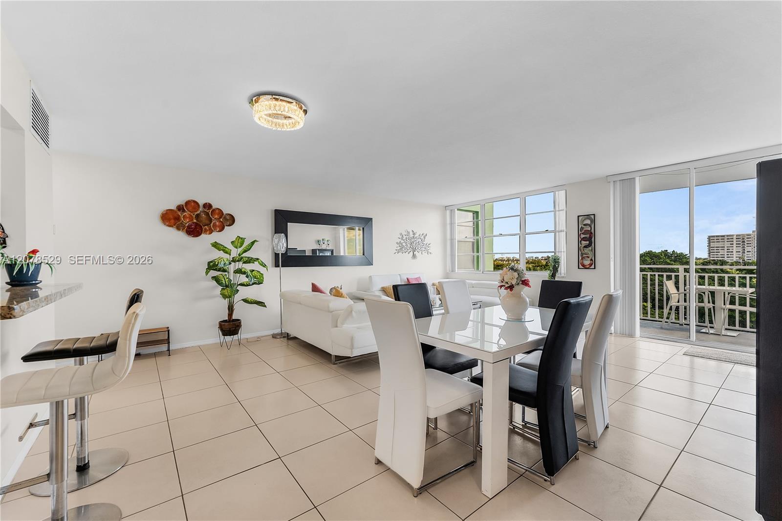 Furnished condo living and dining area with a glass-top table and balcony access.