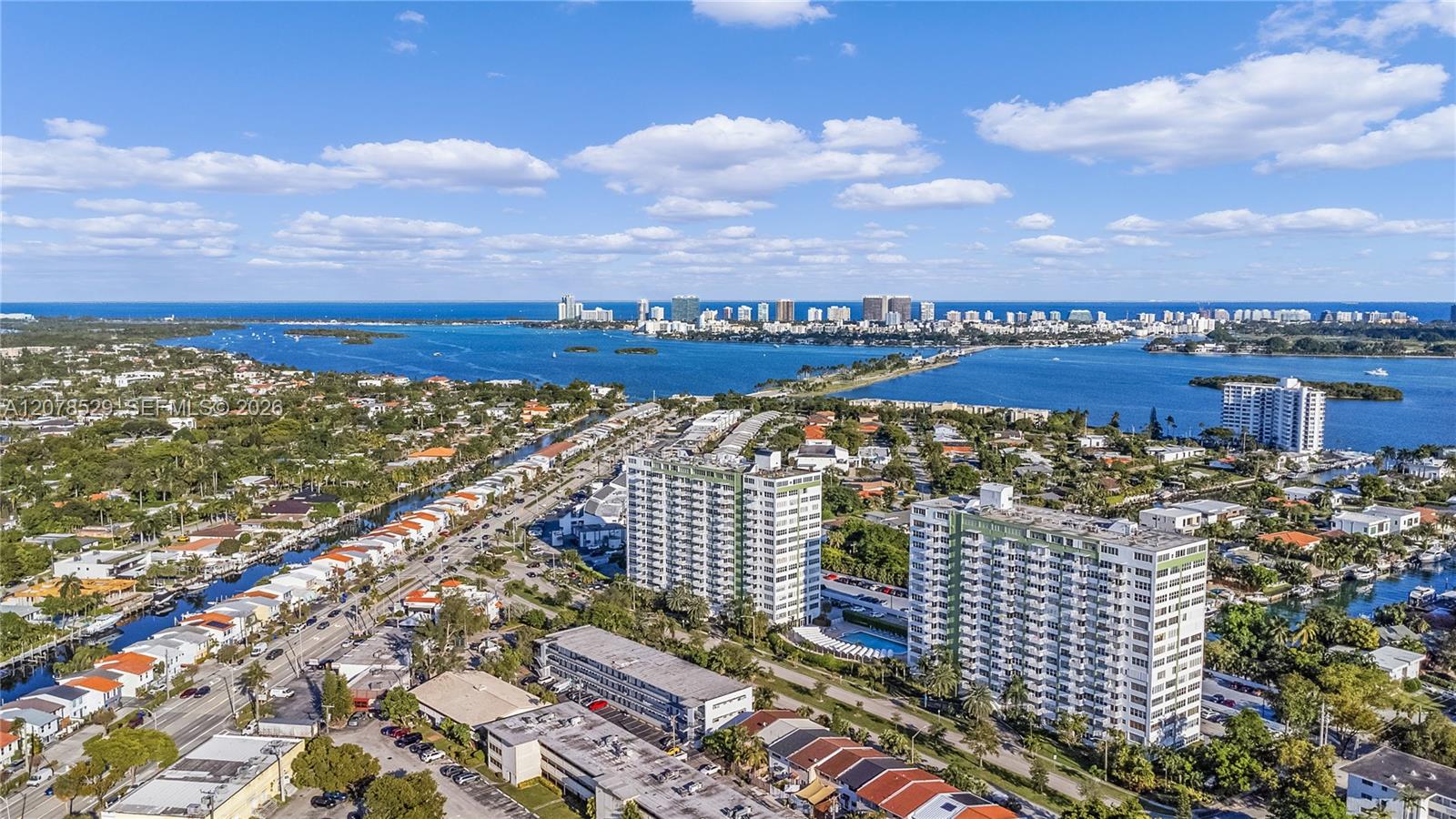 Aerial view of waterfront condos beside Biscayne Bay, with the Miami skyline in the distance.