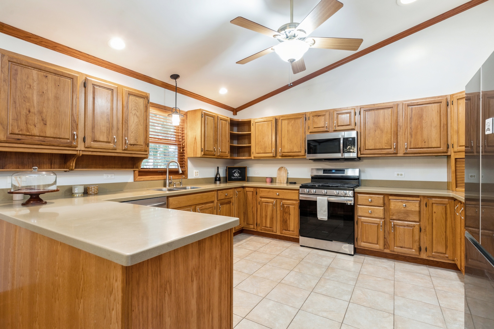 Kitchen with honey-toned wood cabinetry, a large peninsula, and stainless steel appliances.