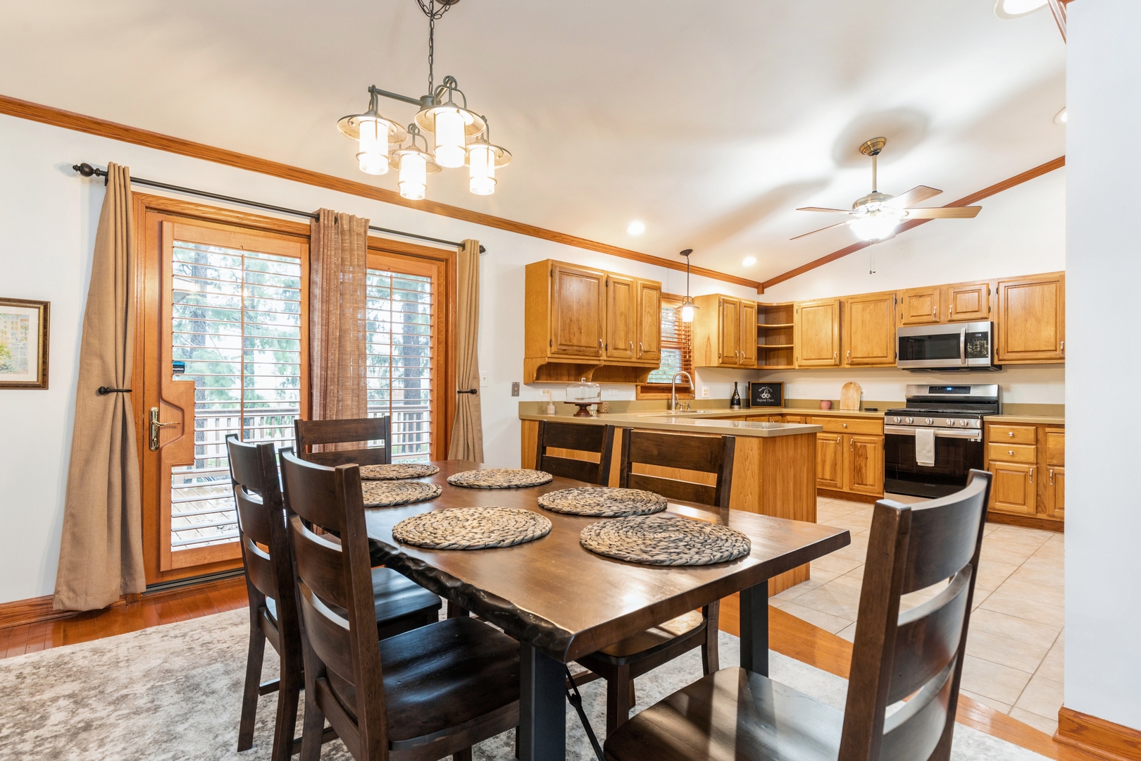 Kitchen and dining area with wood cabinets, a central island, and a dark table by patio doors.