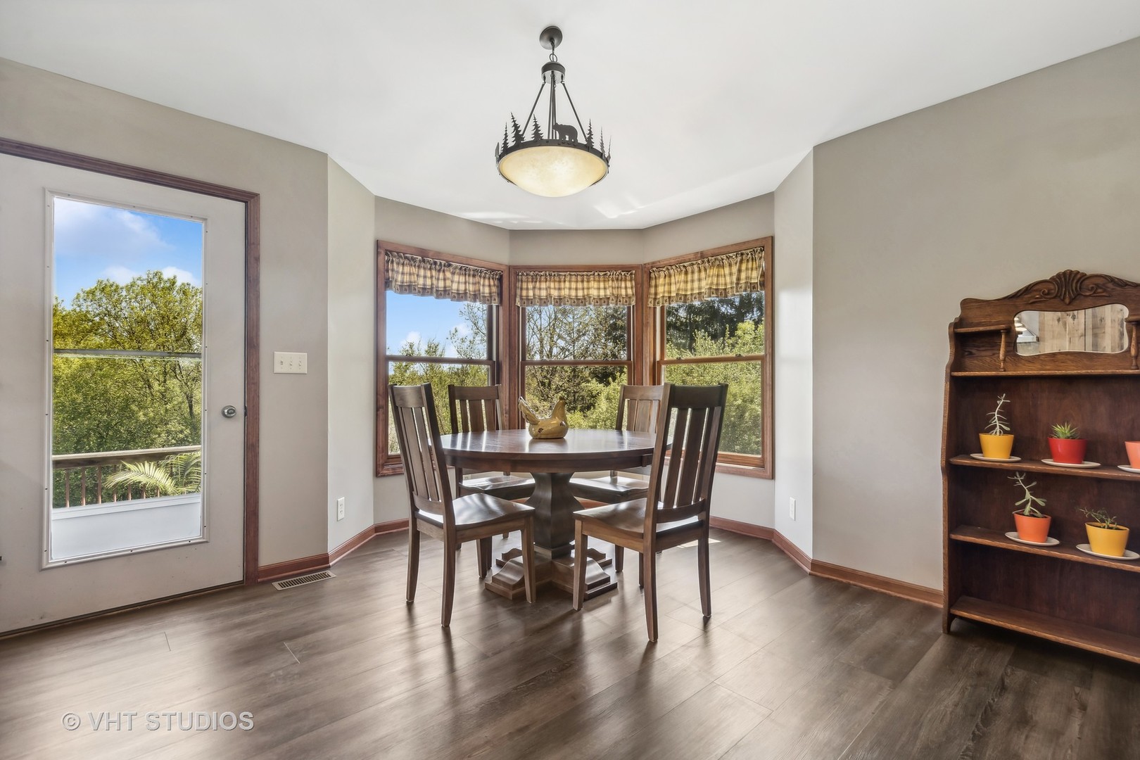 Dining room with a round wooden table, bay windows, and dark wood trim.