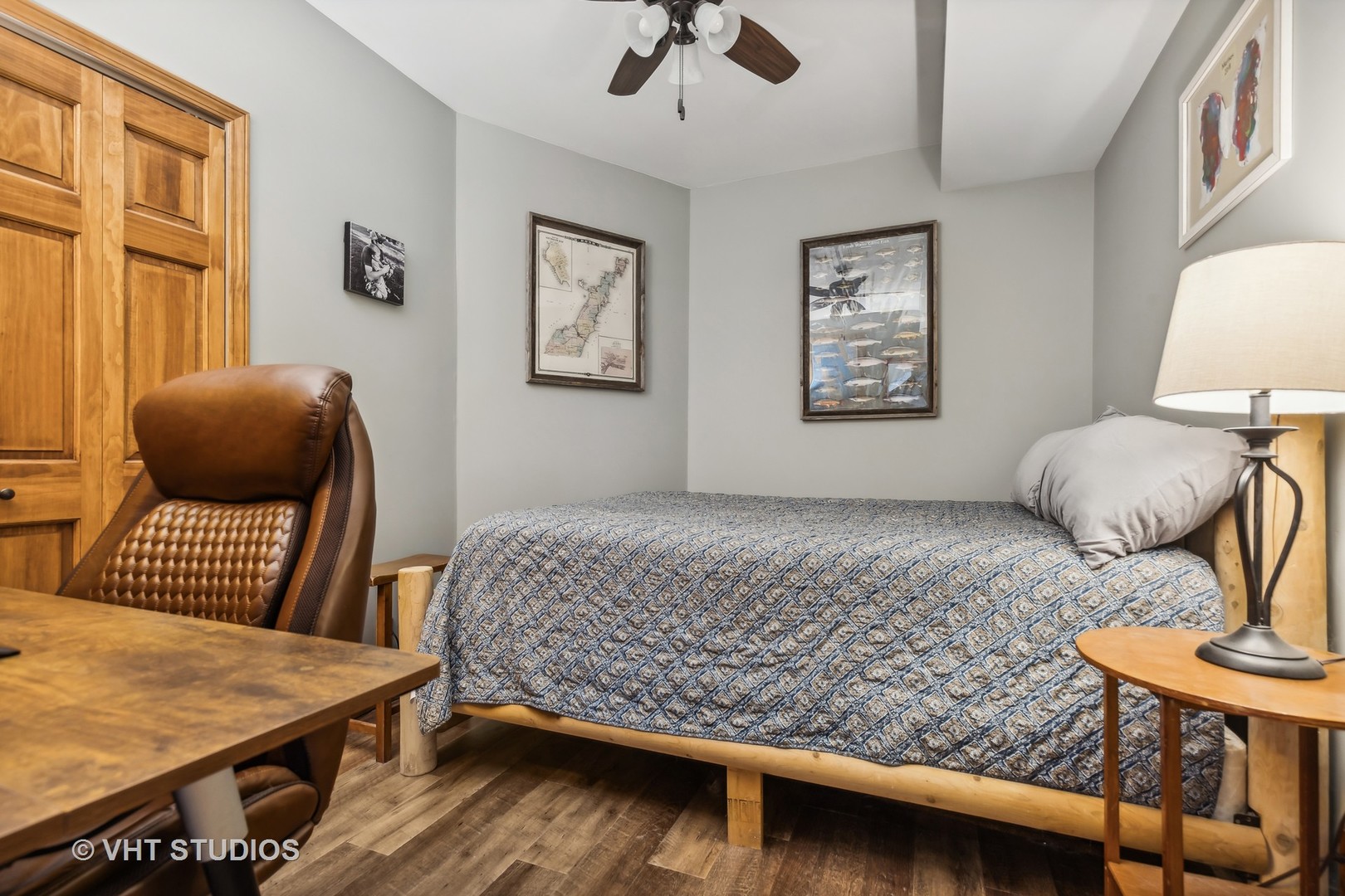 Bedroom with patterned bedding, wooden closet doors, and a brown leather chair.