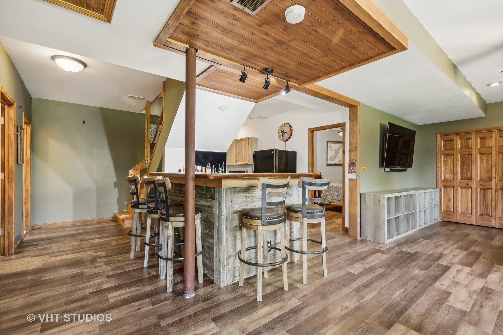 Recreation room with a rustic bar, vaulted wood ceiling, and wood-plank flooring.