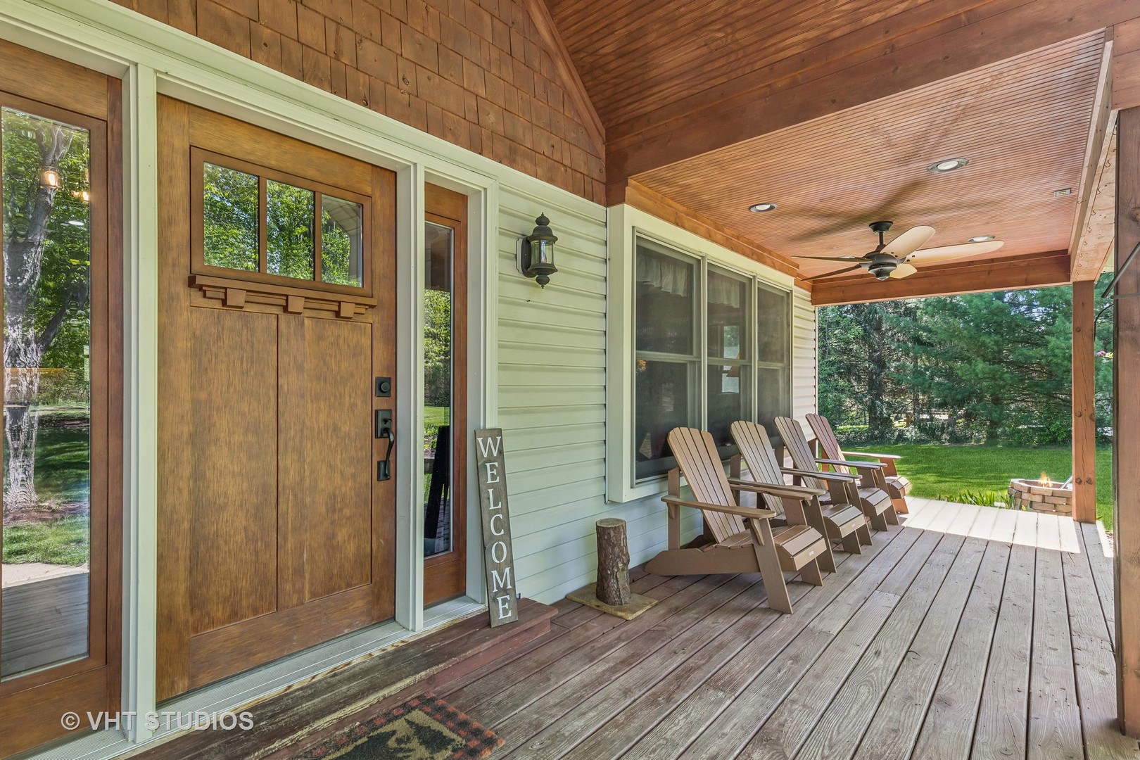 Covered porch with a wooden entry door, vaulted wood ceiling, and Adirondack chairs.