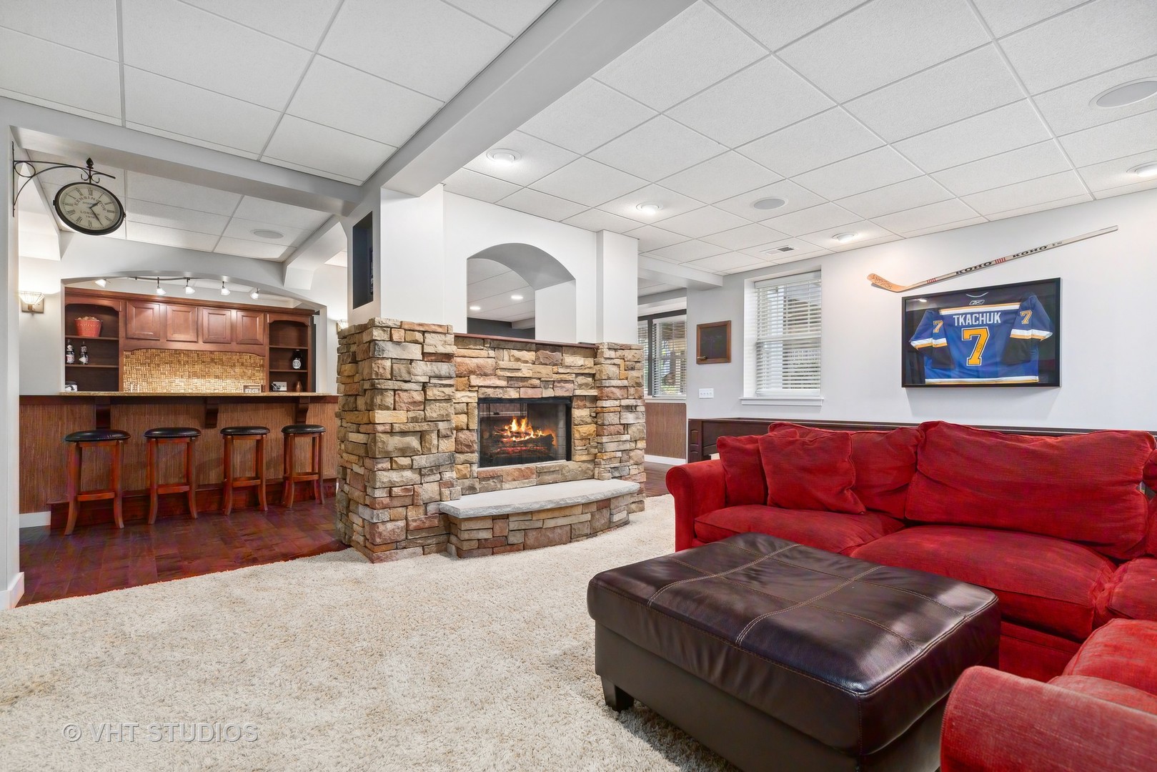 Recreation room with a stone fireplace, built-in bar, and red sectional sofa.
