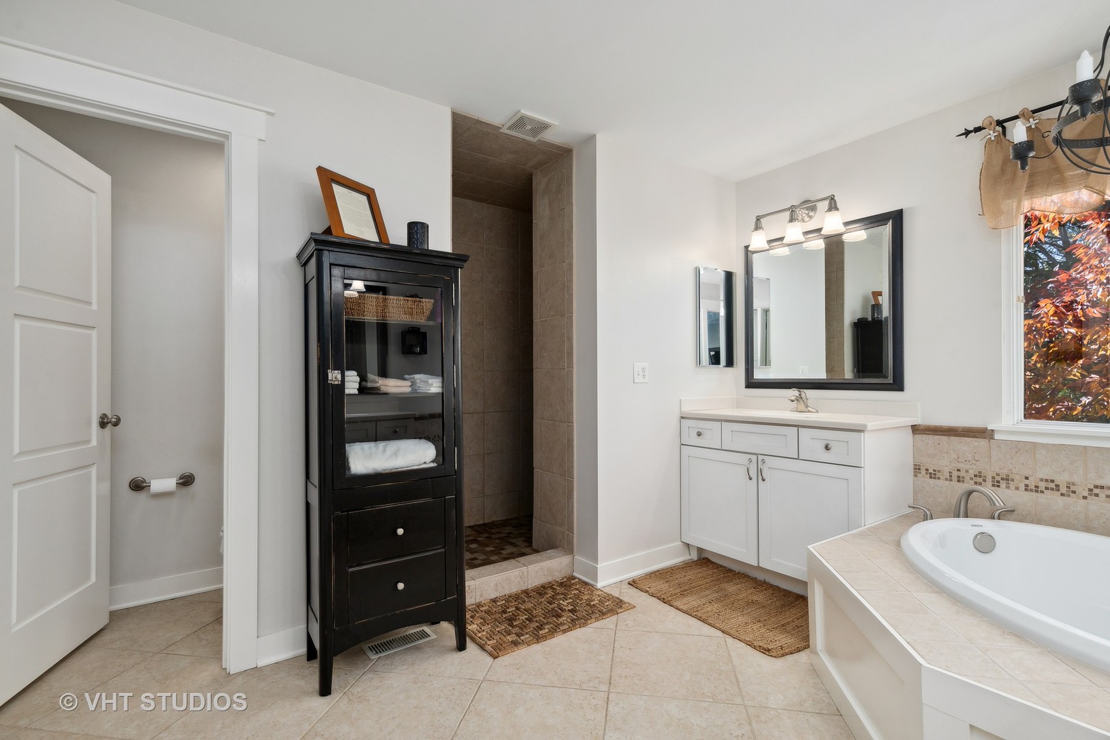 Bathroom with a tiled walk-in shower, white vanity, and built-in soaking tub.