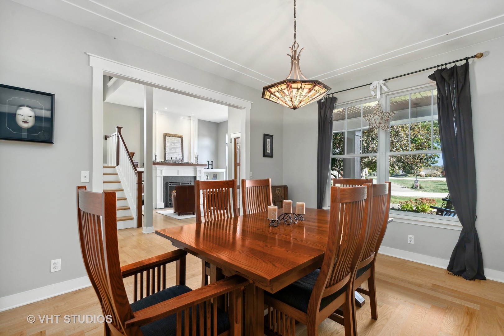 Dining room with a wooden table, stained-glass pendant, and windows overlooking the yard.