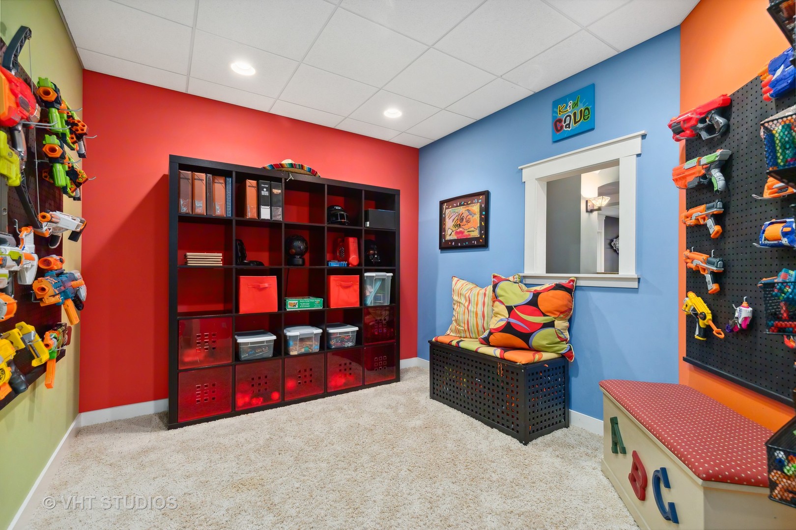 Colorful playroom with toy blasters on the walls, black cubby shelves, and a cushioned bench.