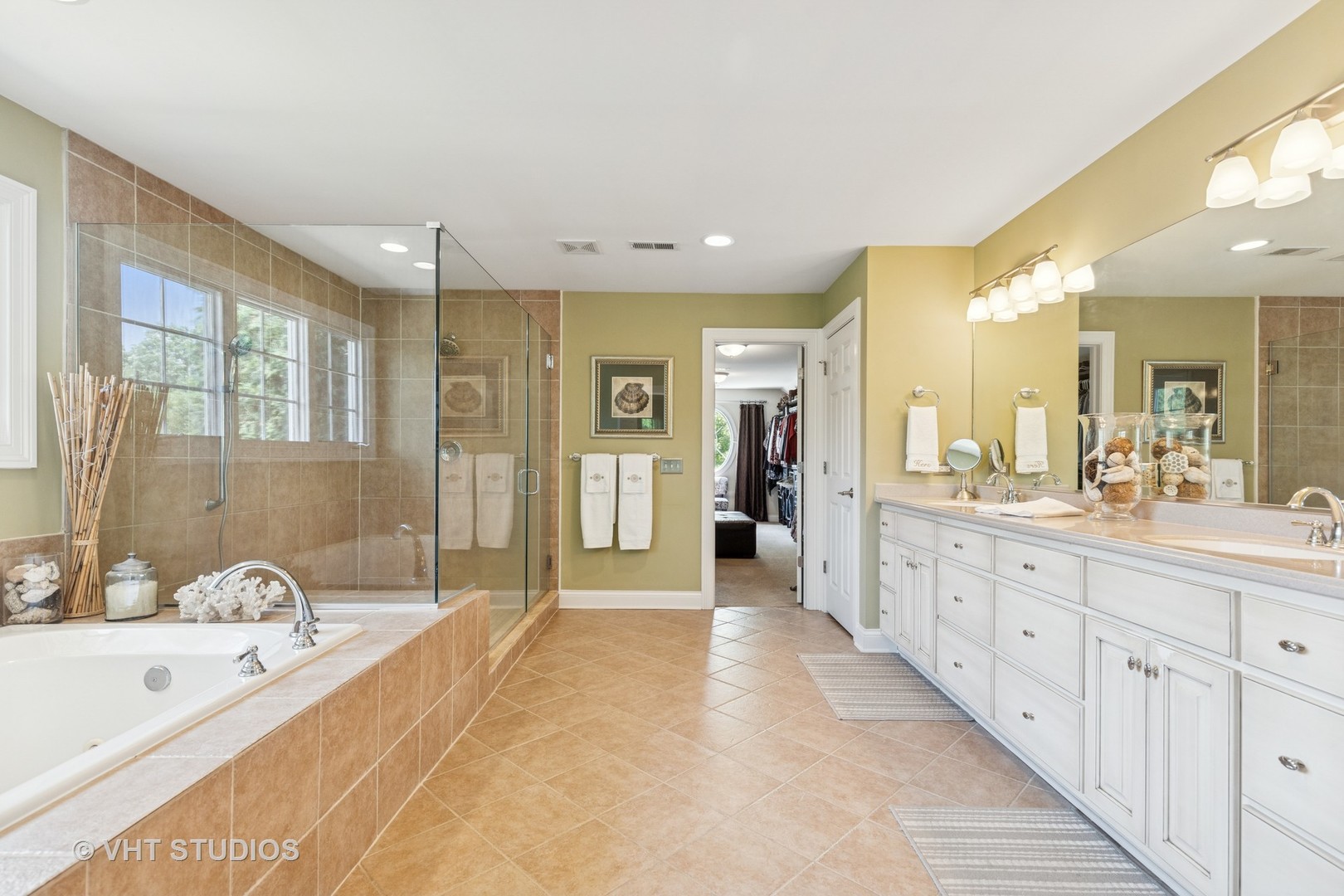 Spacious tiled bathroom with a glass shower, soaking tub, and long white double vanity.