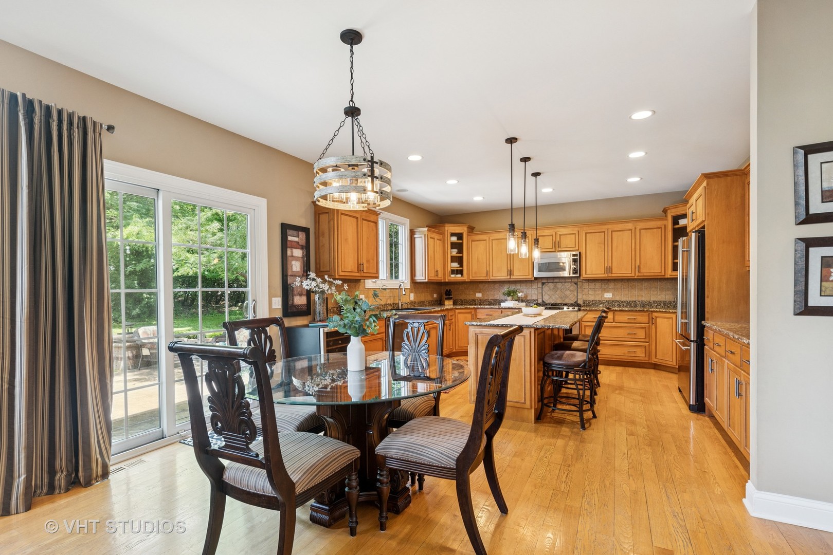 Kitchen and dining area with warm wood cabinets, a central island, and a glass dining table by sliding doors.