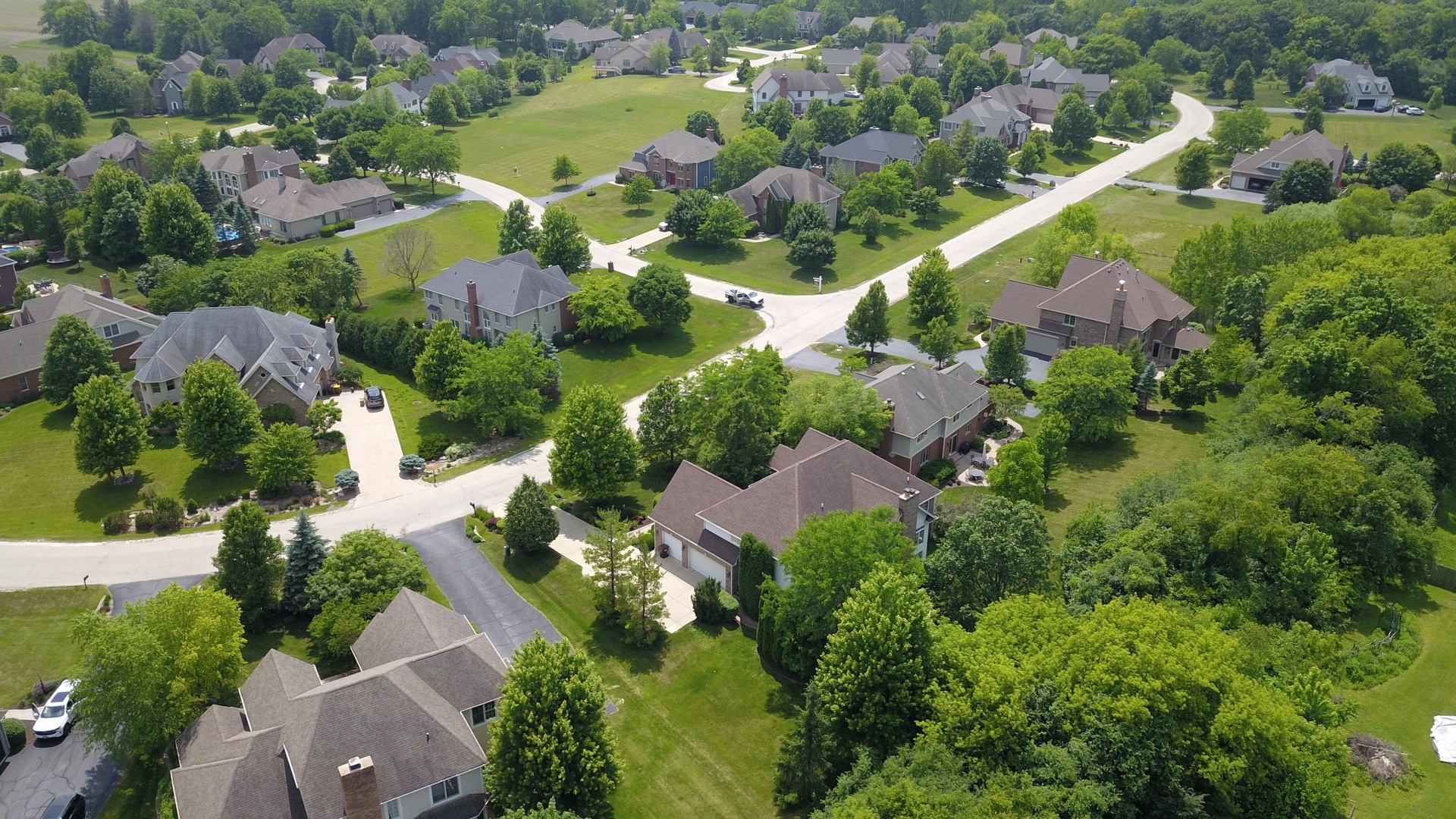 Aerial view of a leafy residential neighborhood with detached homes and curving streets.