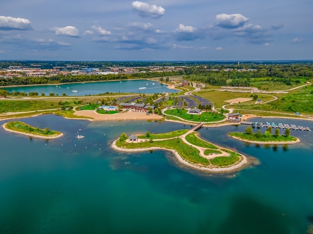 Aerial view of a turquoise lake with landscaped islands, walking paths, and docks.