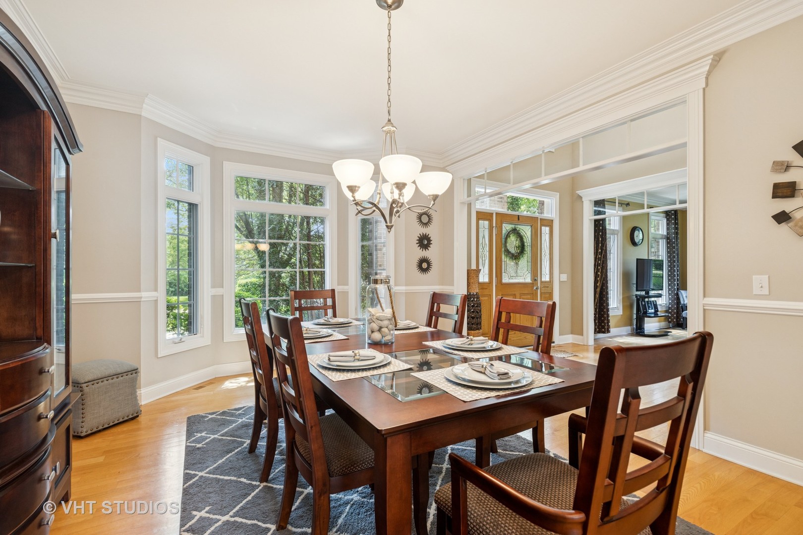 Dining room with a set table, dark wood chairs, large windows, and a chandelier.