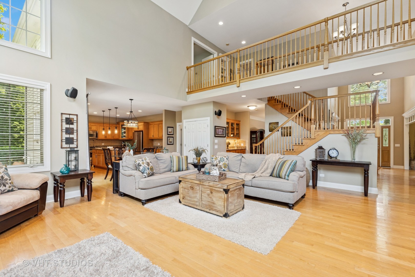 Living room with vaulted ceilings, an open loft, hardwood floors, and a staircase.