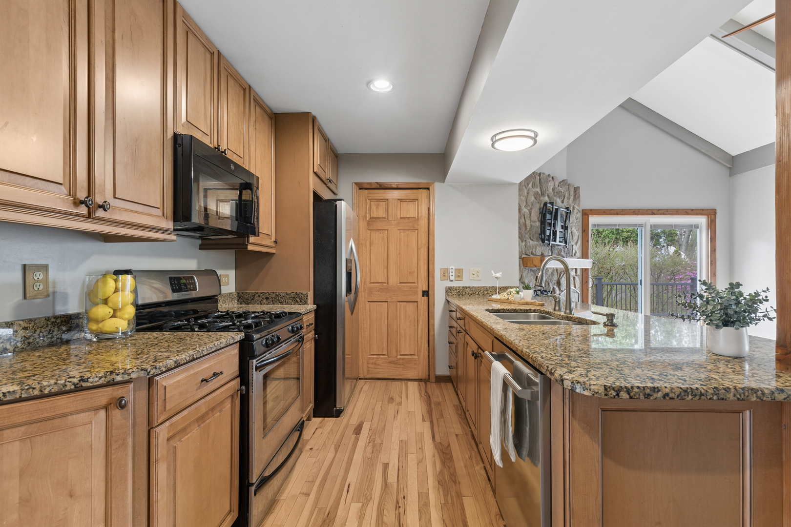 Kitchen with wood cabinets, granite island, double sink, and sliding doors to a balcony.