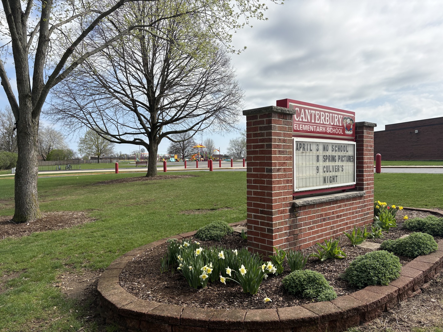Canterbury Elementary School sign beside landscaped grounds and a playground.