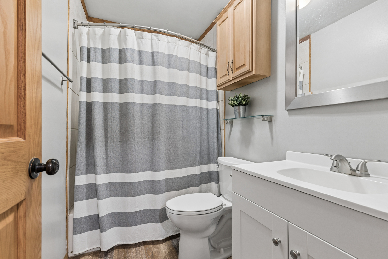 Bathroom with a white vanity, toilet, and gray-and-white striped shower curtain.