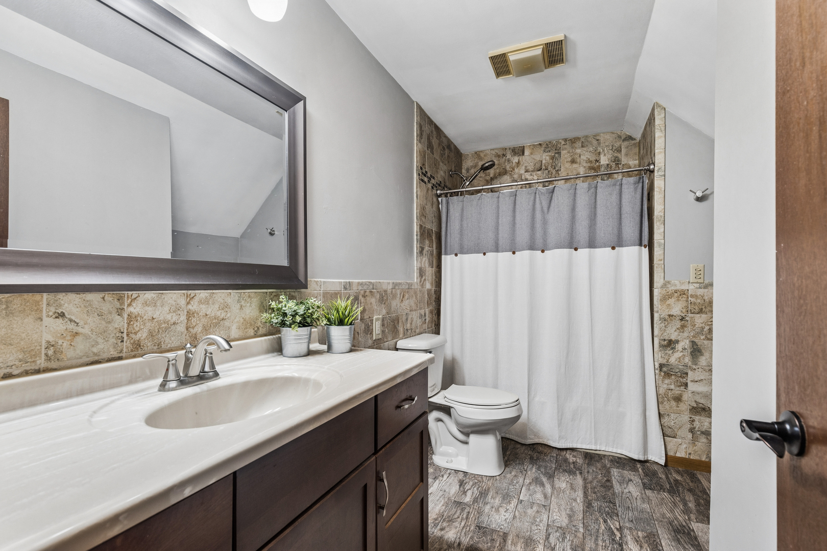 Bathroom with a dark wood vanity, large mirror, and tiled tub surround.