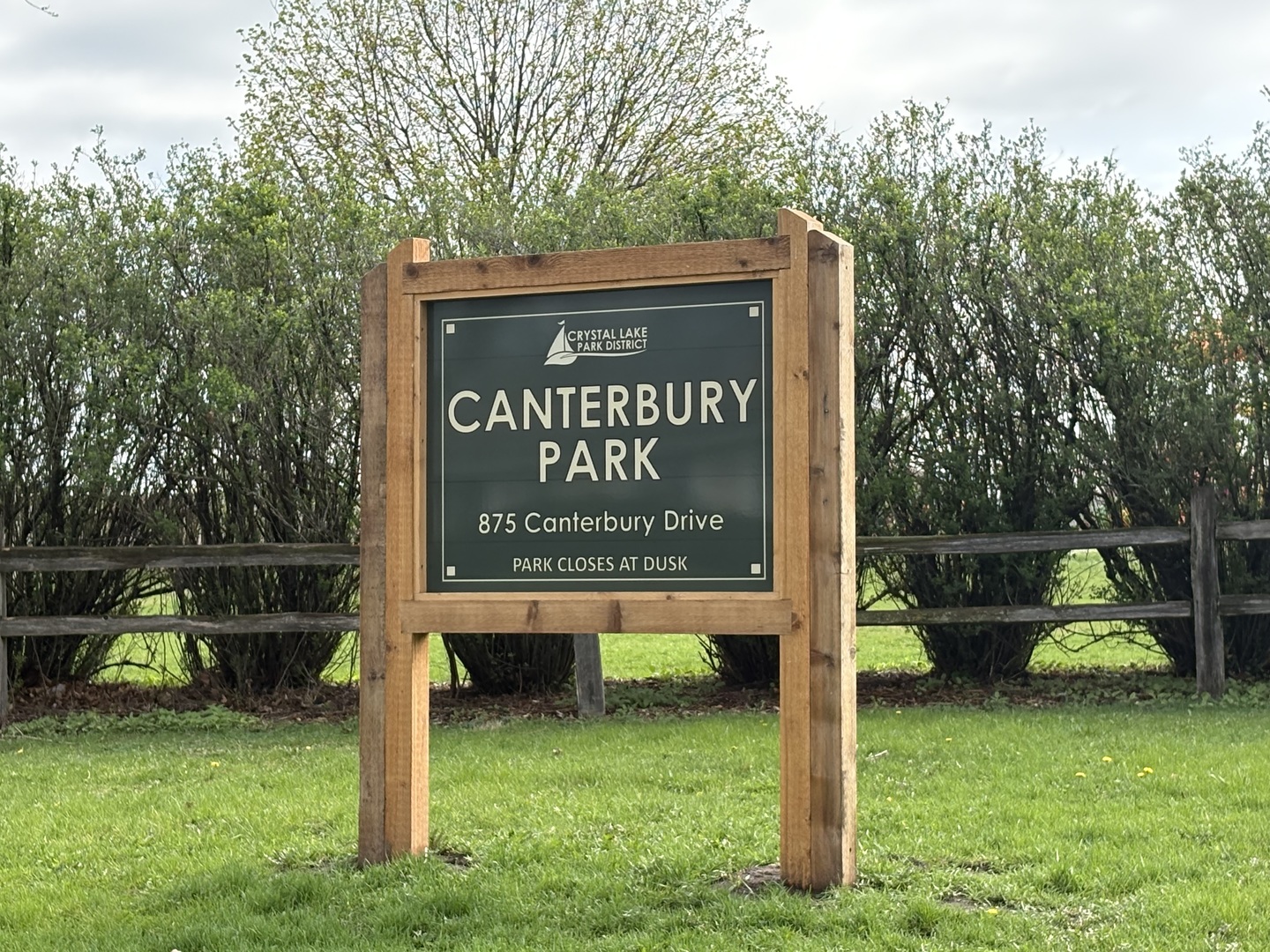Canterbury Park sign at 875 Canterbury Drive, framed by grass and trees.