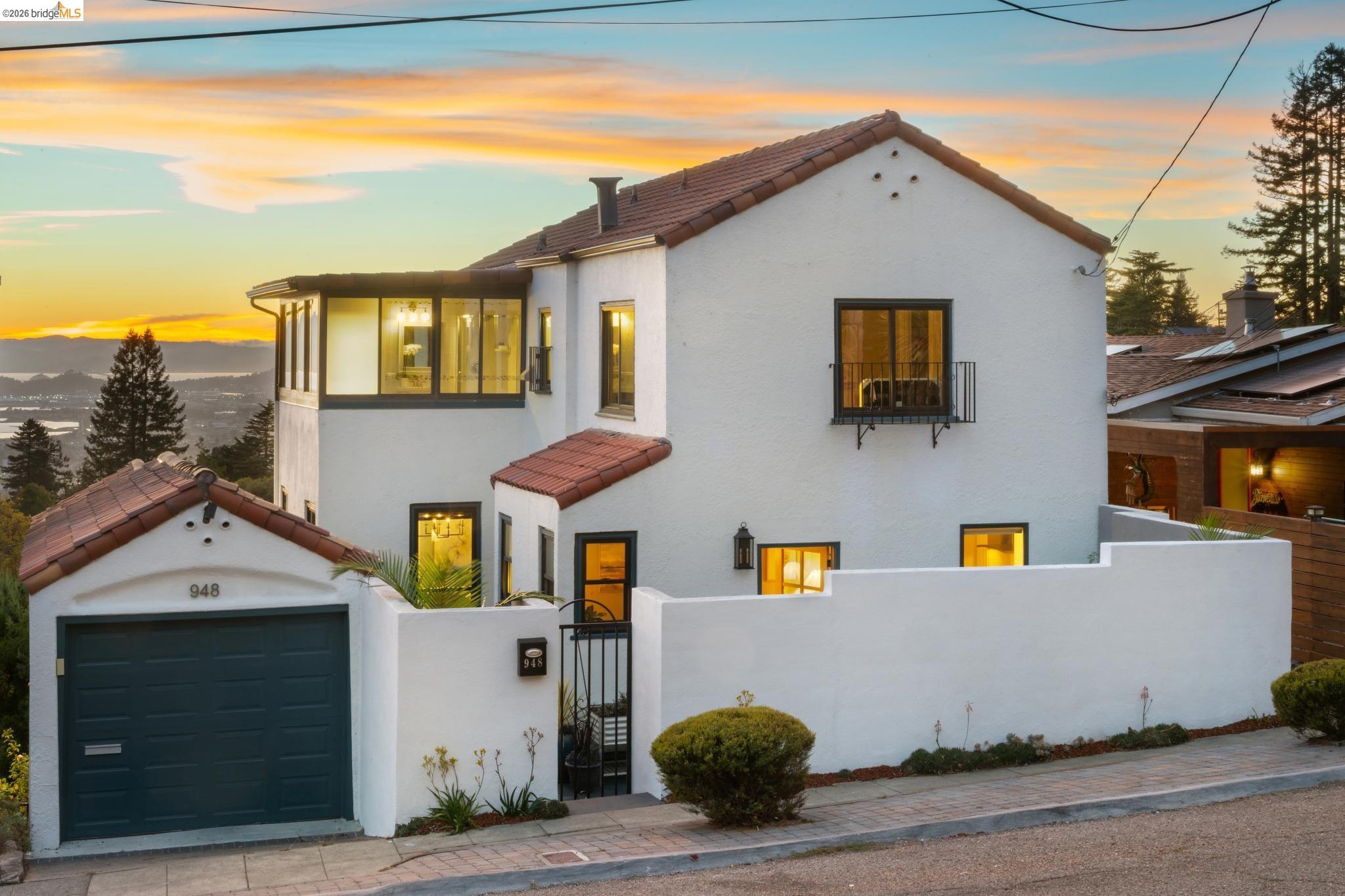 White stucco home with a terracotta tile roof and walled entry courtyard at sunset.