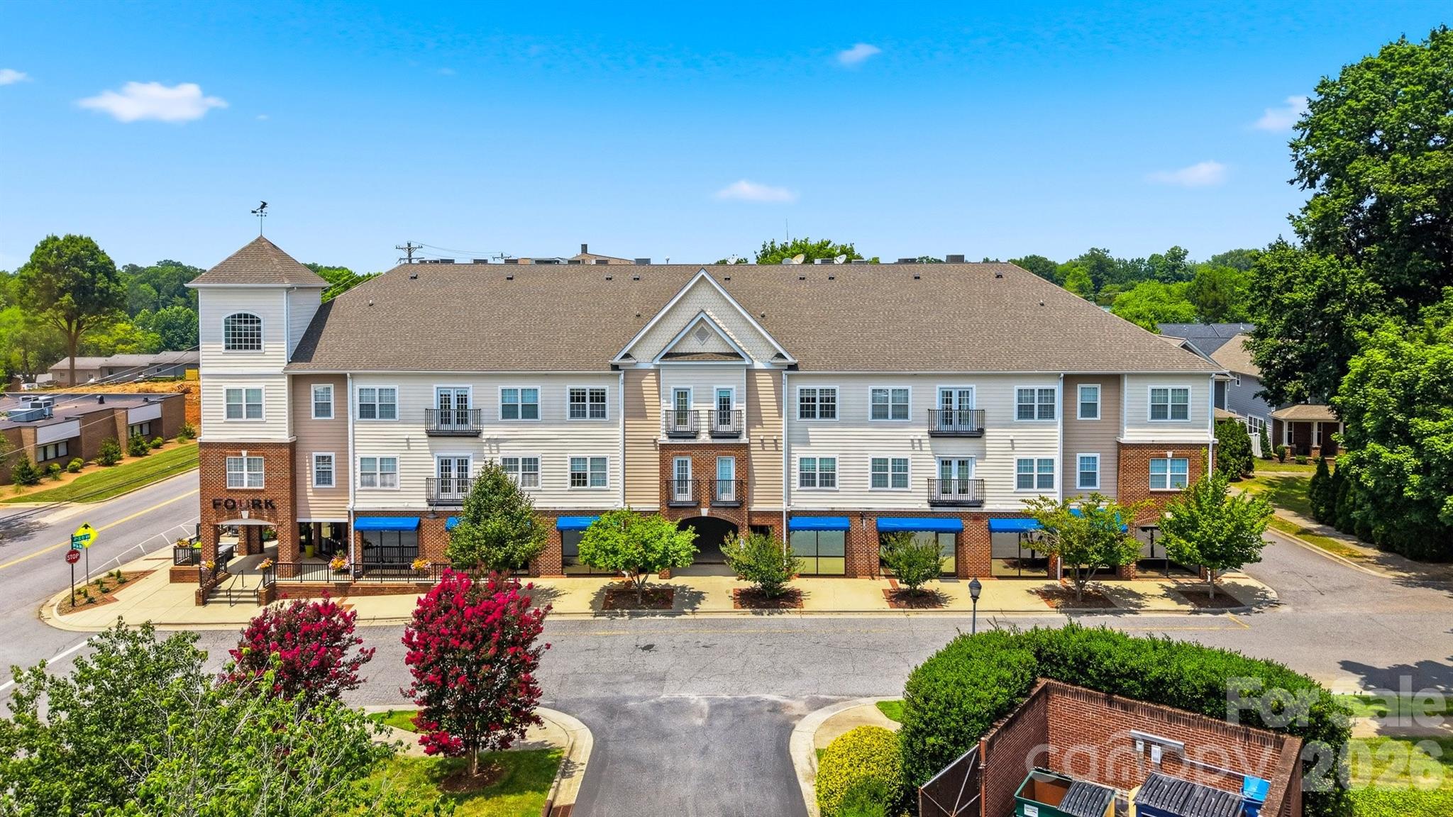 Multi-story apartment building with ground-floor storefronts, balconies, and blue awnings.